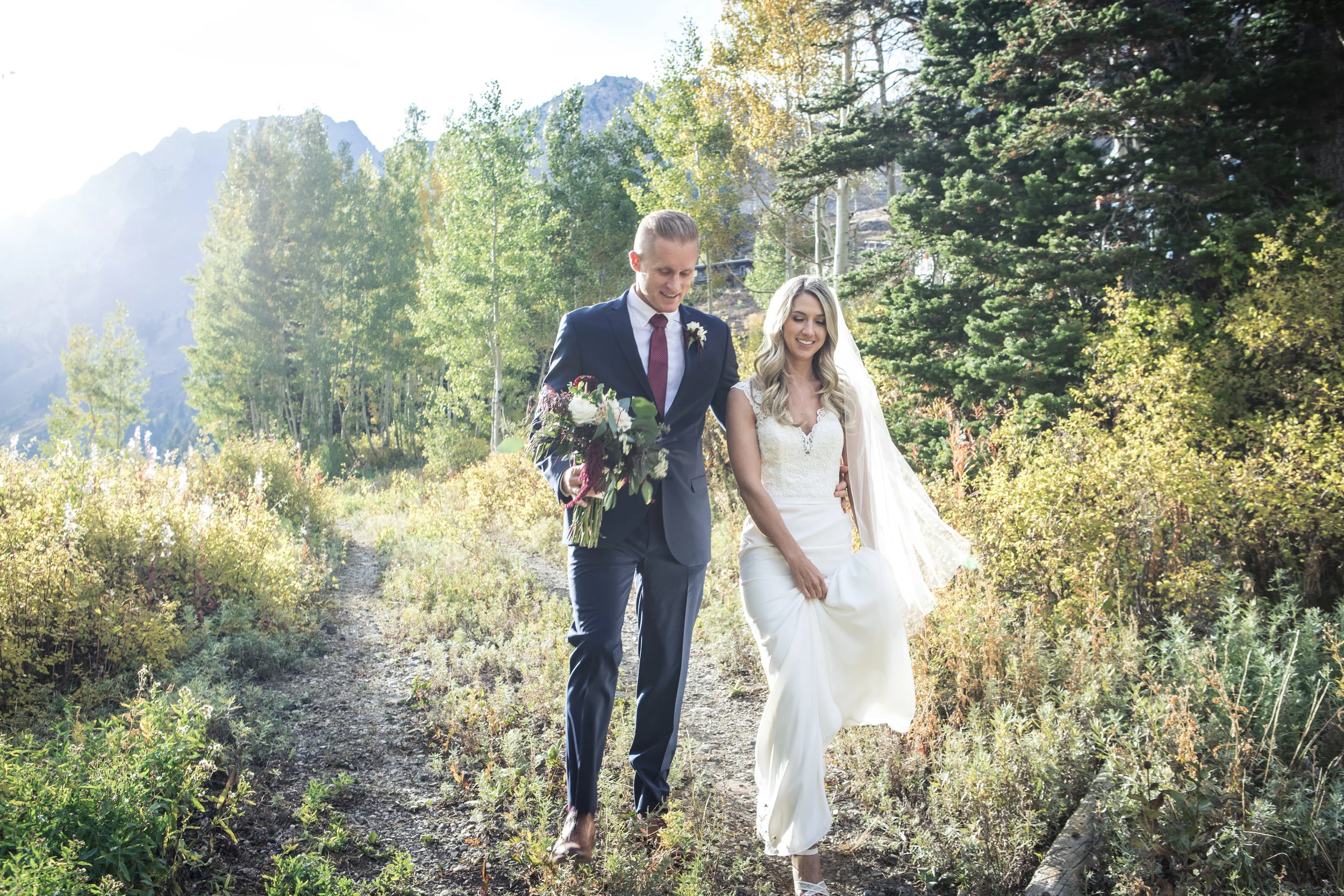  Bride and Groom walk through forest after wedding. Alta Utah 