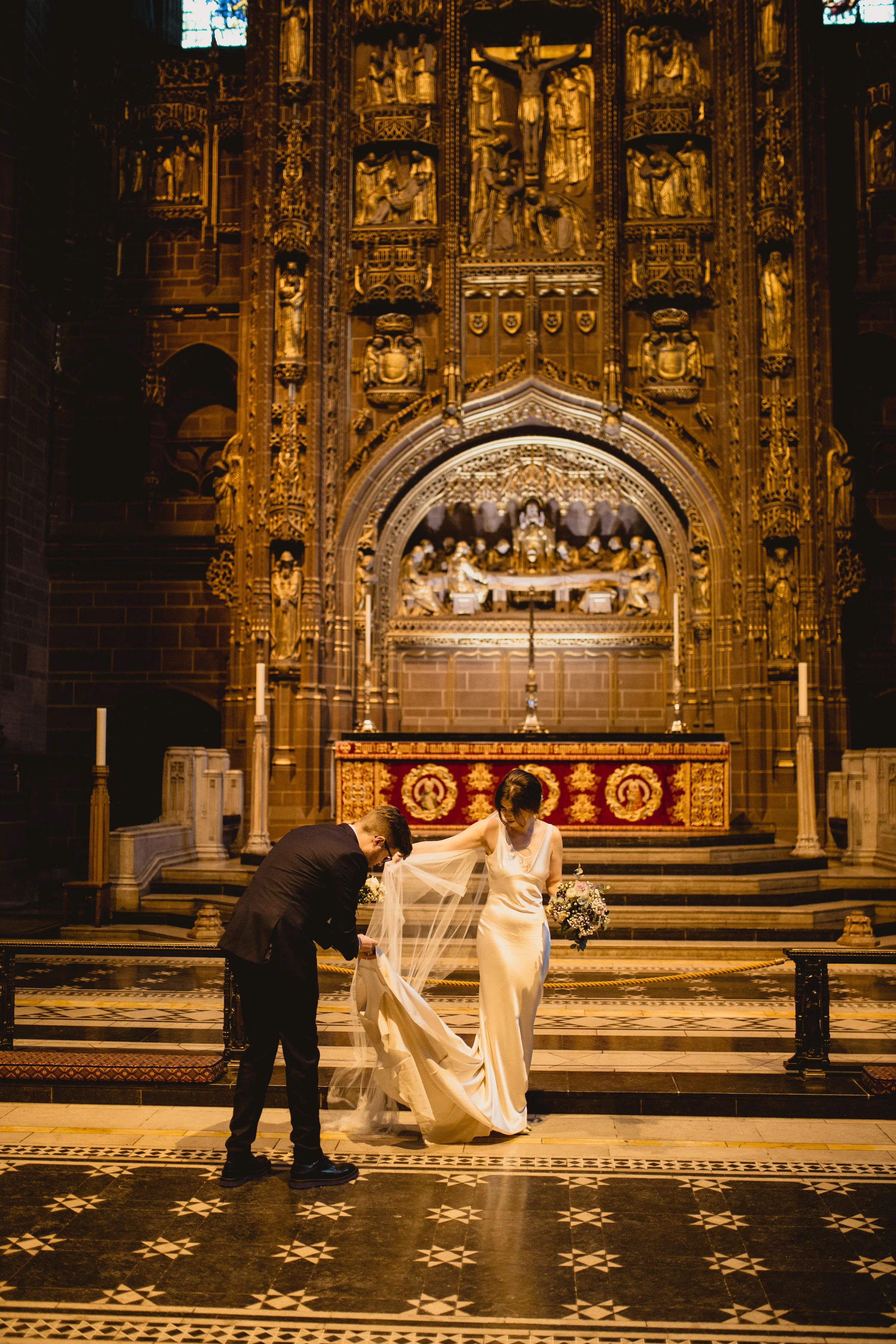 Groom helping bride with dress Liverpool cathedral wedding photographer