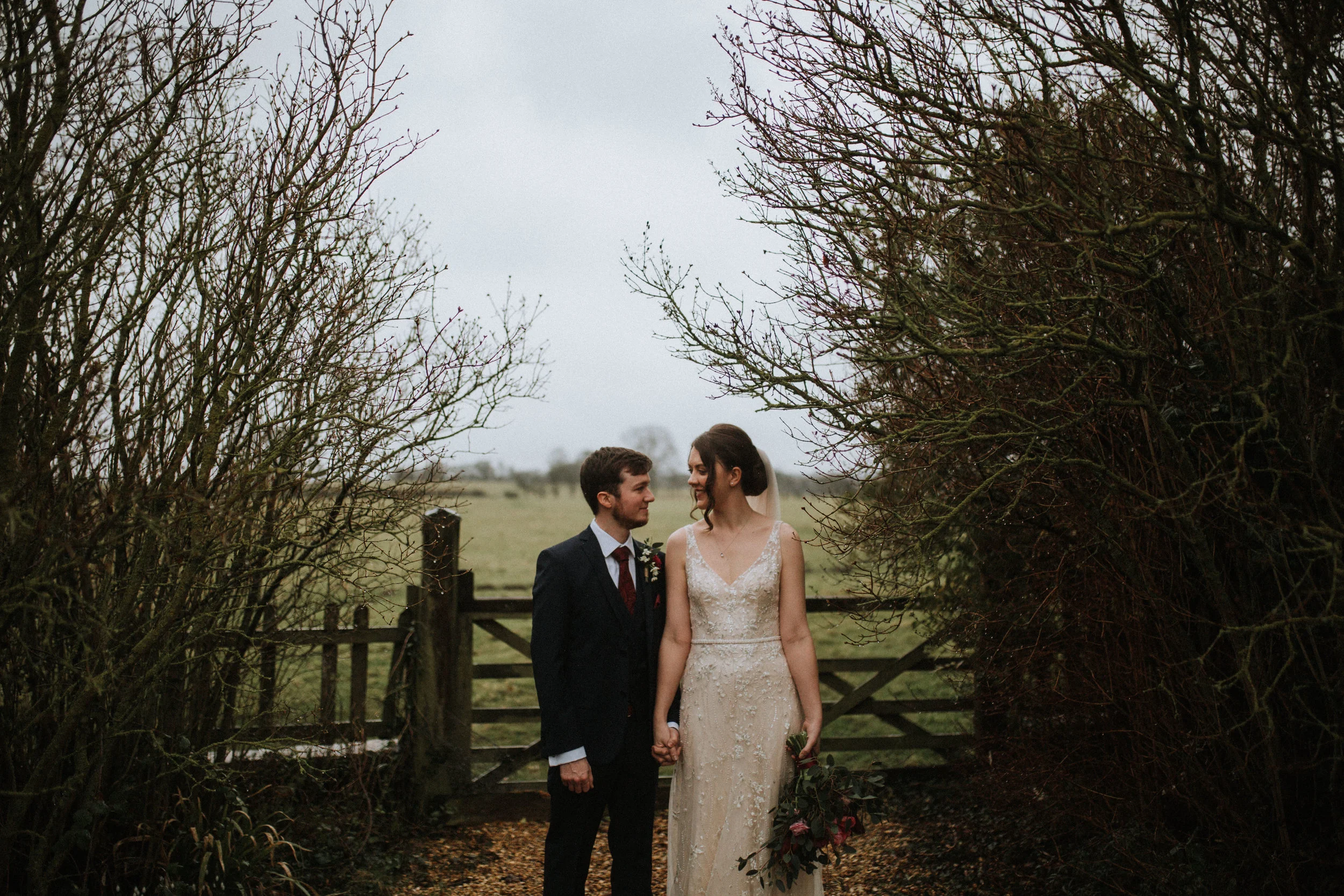 Bride and groom standing with trees at Hornington Manor