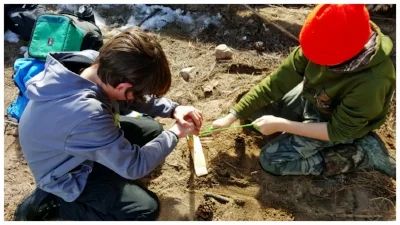 Two students working on a tag-team primitive bow-drill fire