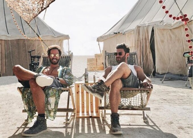  two men in burning man festival in front of their survival tent 