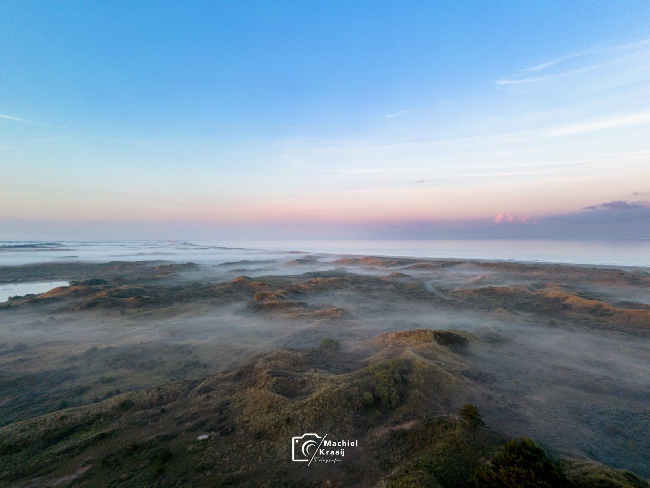 Mistige zonsopkomst over de duinen.