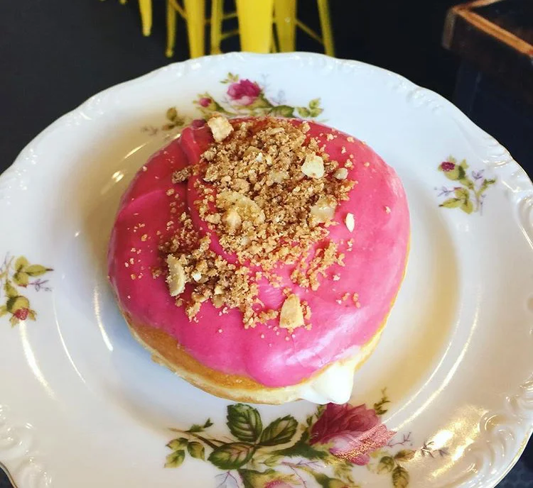 Raspberry Cream - Raspberry icing, cream cheese filling topped with a mini donut-honey-nut streusel.