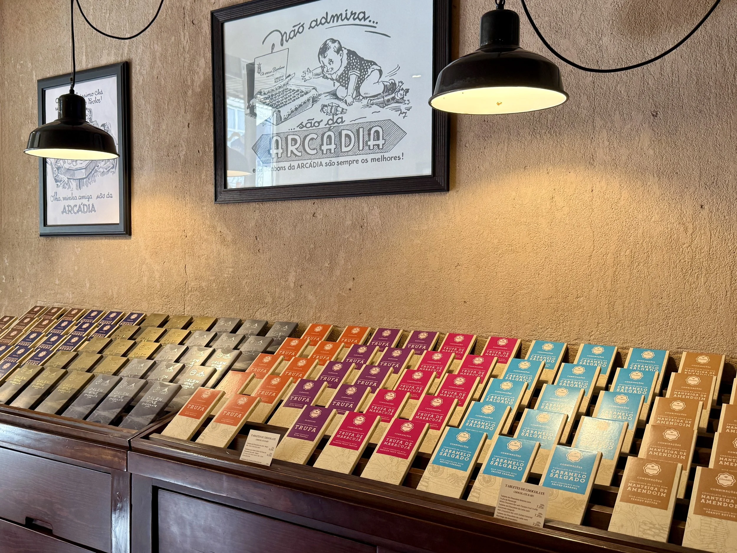 An inviting display of chocolate bars arranged by color and flavor at Arcádia Chocolates’ Chiado confectionery