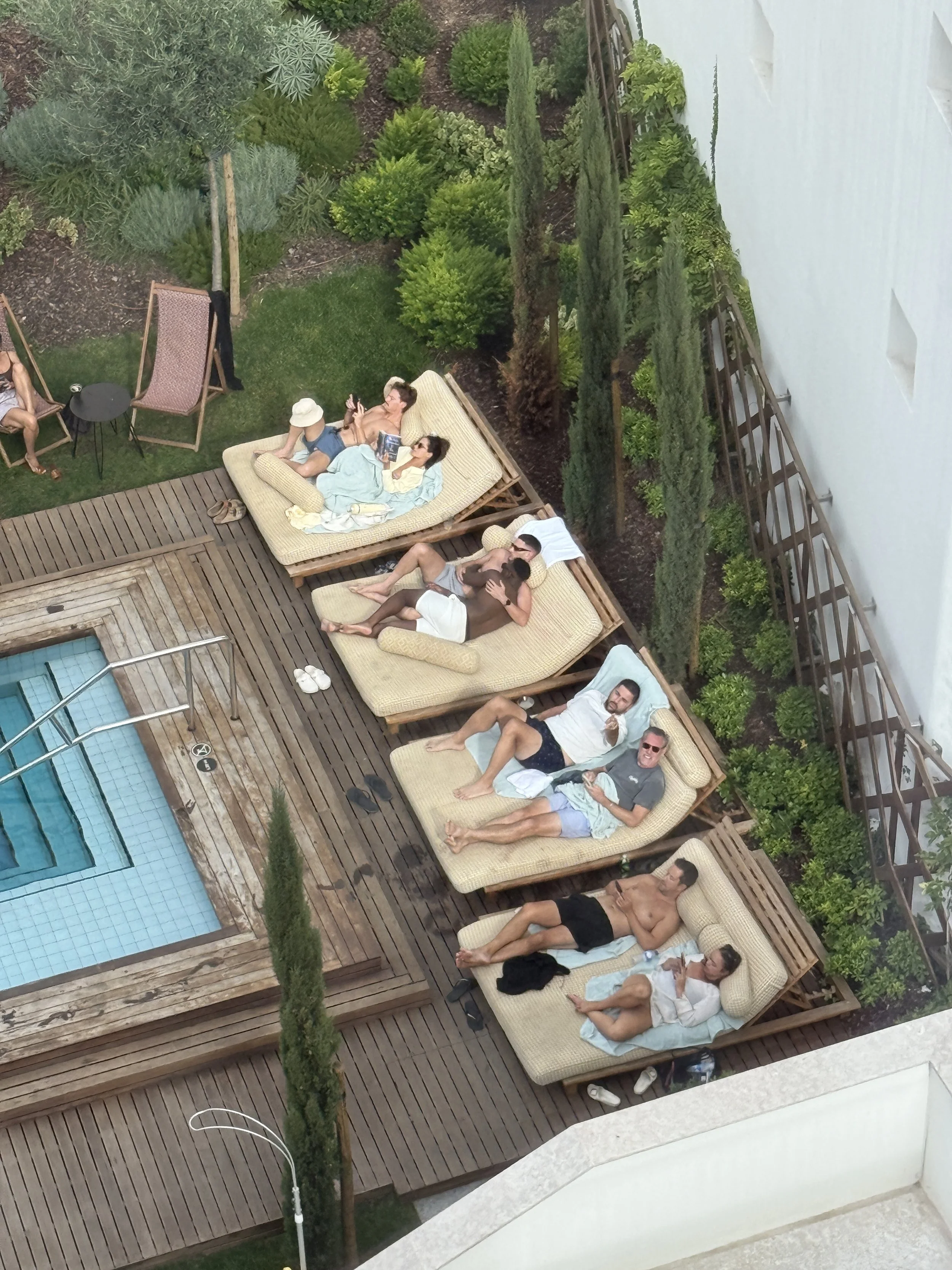 People lay on double lounge chairs by the pool at Locke de Santa Joana in Lisbon