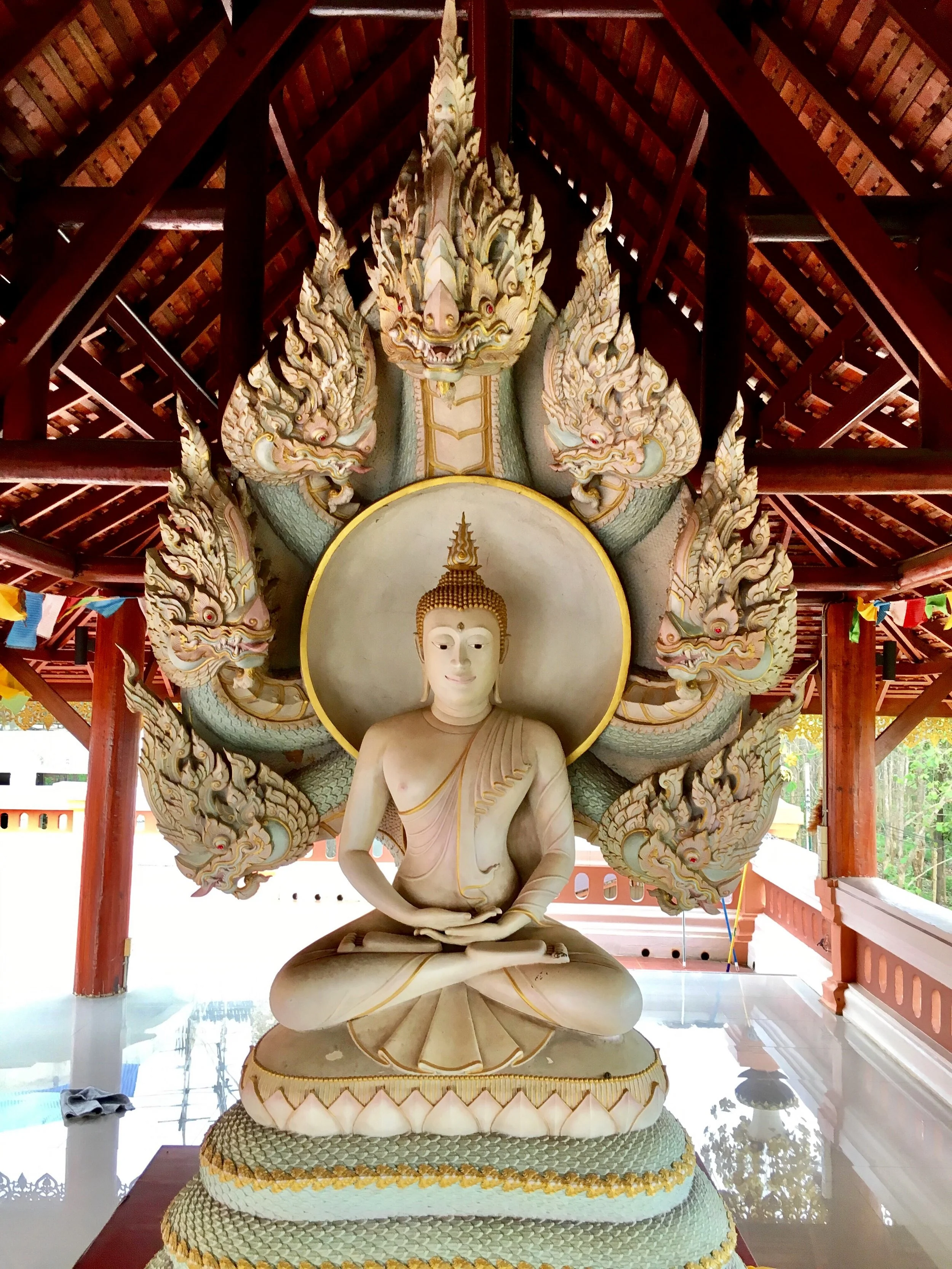 A pale blue and white Buddha in the open-aired sala