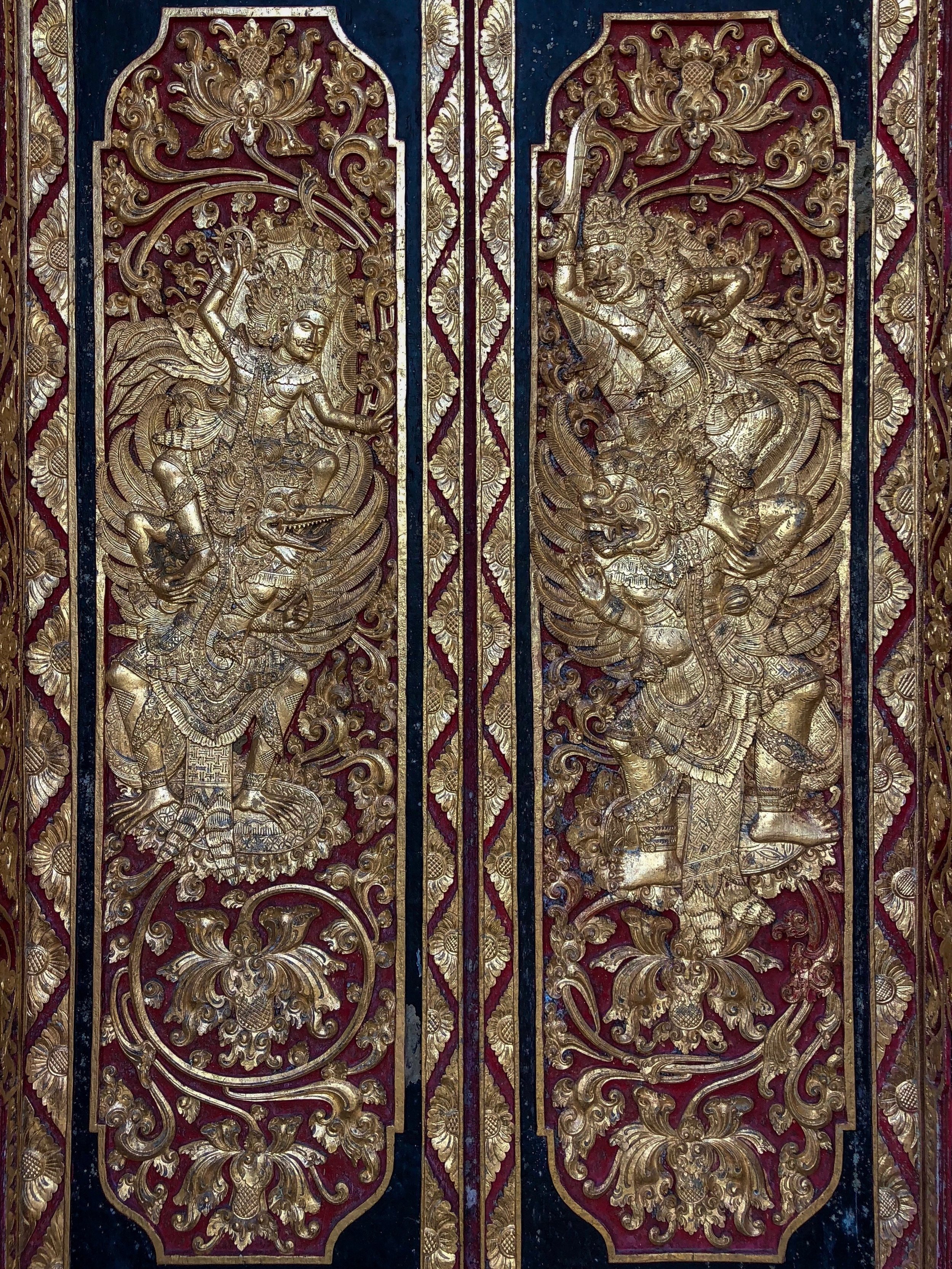 The door detail on the entrance gate shows the god Vishnu, riding his eagle mount Garuda and battling a pair of rakshasa demons
