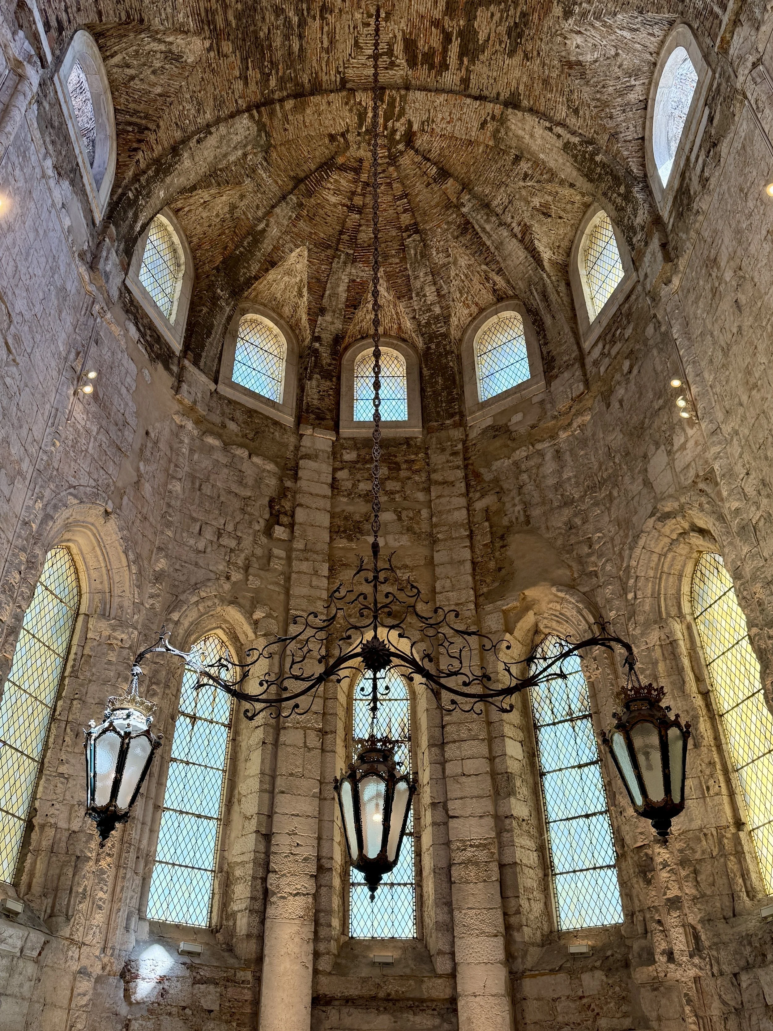 A wrought-iron chandelier hangs beneath the weathered Gothic vault of one of the Carmo church’s surviving apse chapels