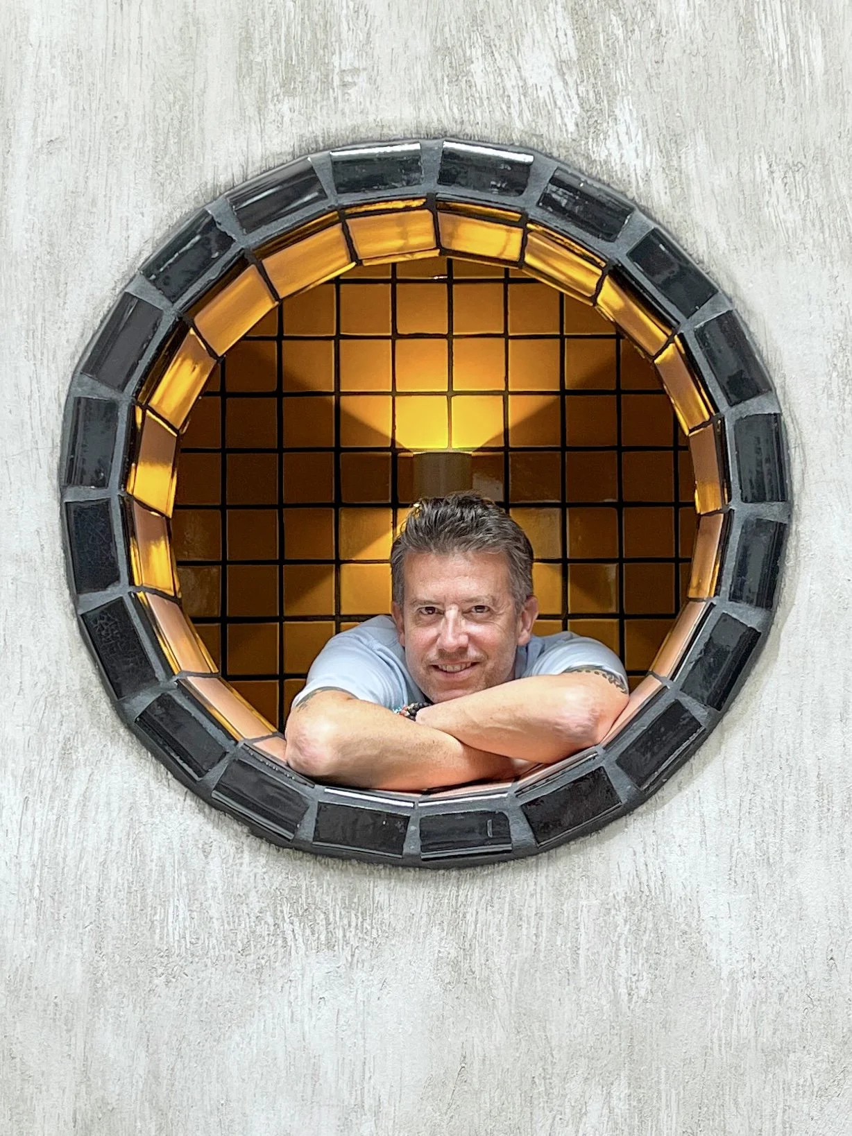 Man looking through round window at Casa Hoyos in San Miguel de Allende