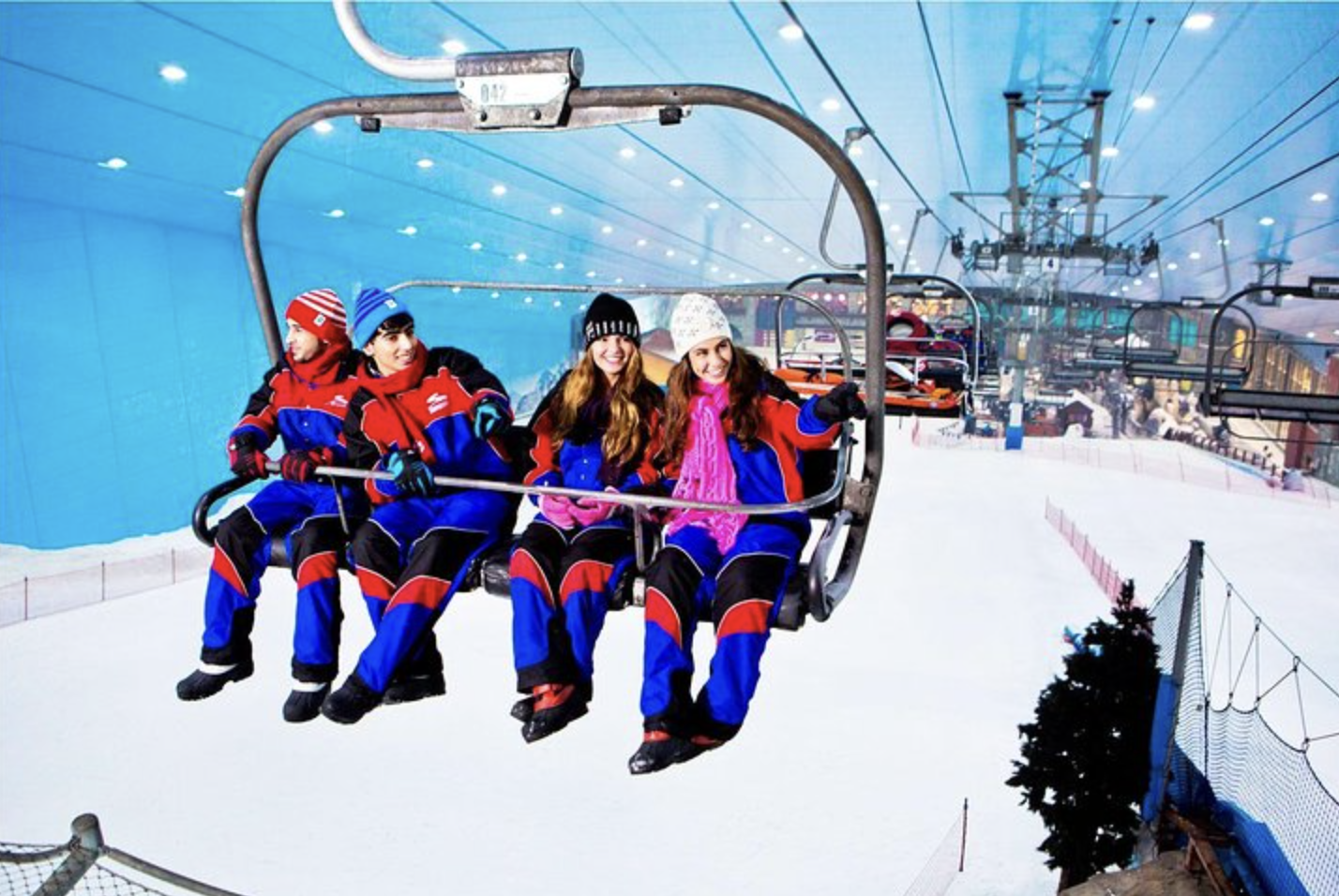 Four people sit on a chairlift in an indoor ski resort in Dubai, UAE