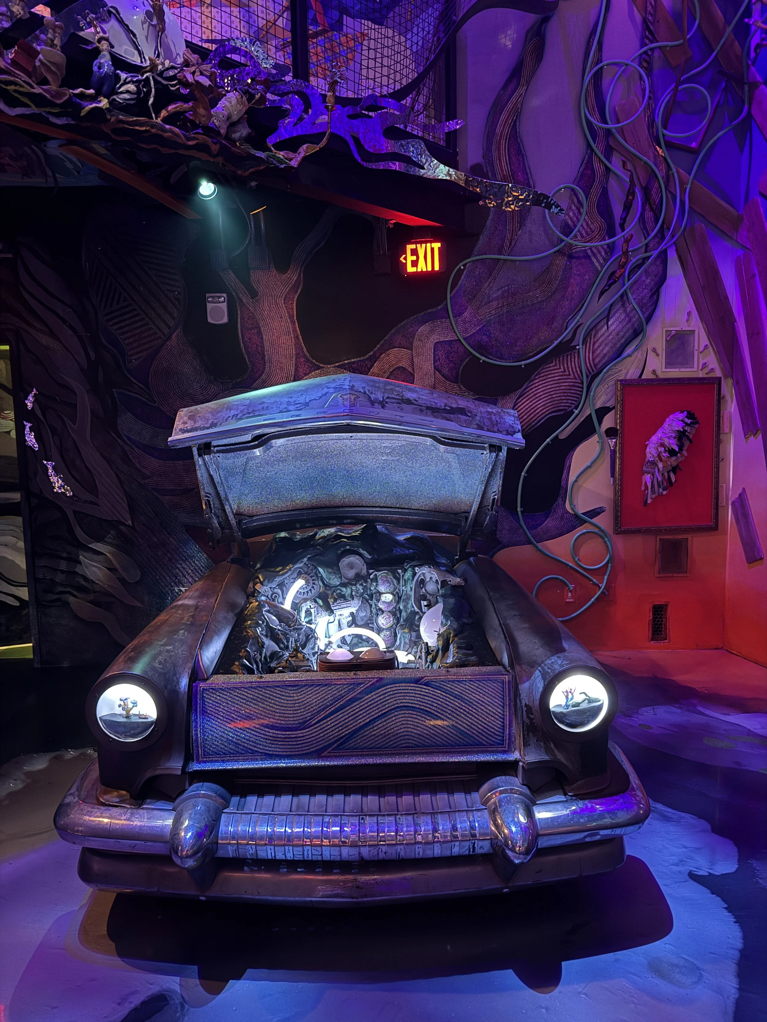 A strange car with its hood open at Meow Wolf Radio Tave in Houston, Texas