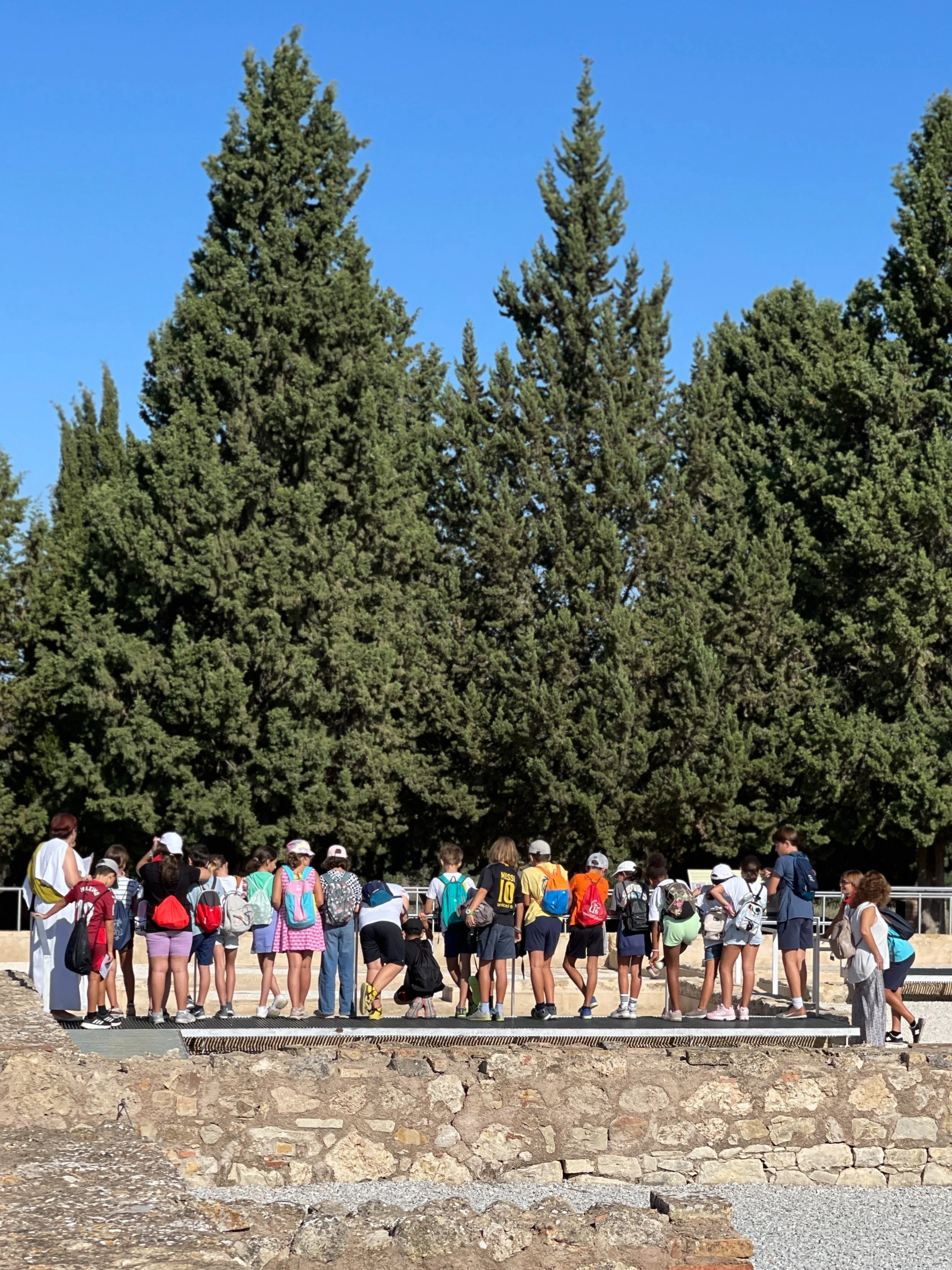 A row of schoolchildren look at the mosaics at Italica in Spain