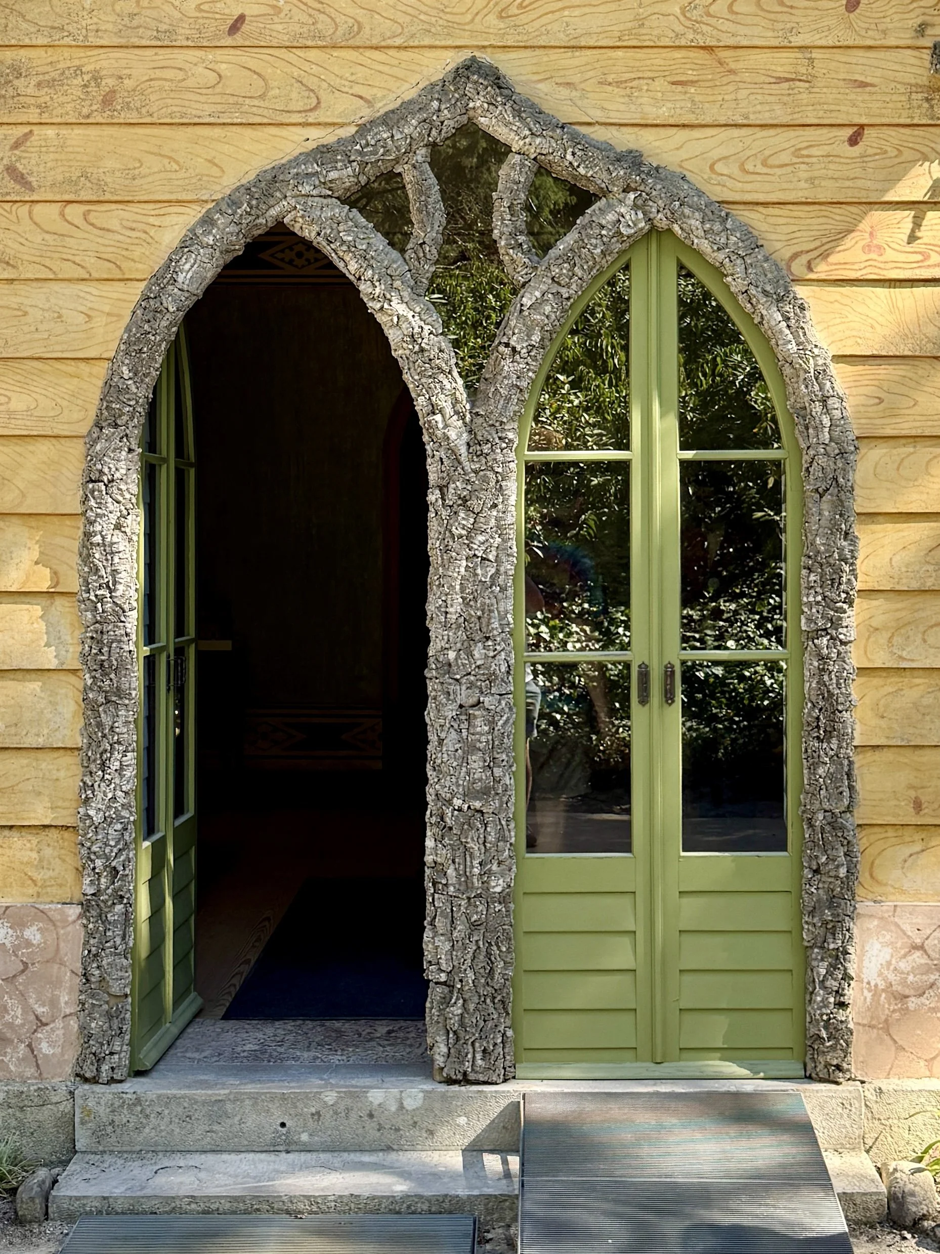 Two sets of green arched doorways lined in cork trees at the Chalet da Condessa d’Edla in Sintra, Portuagal
