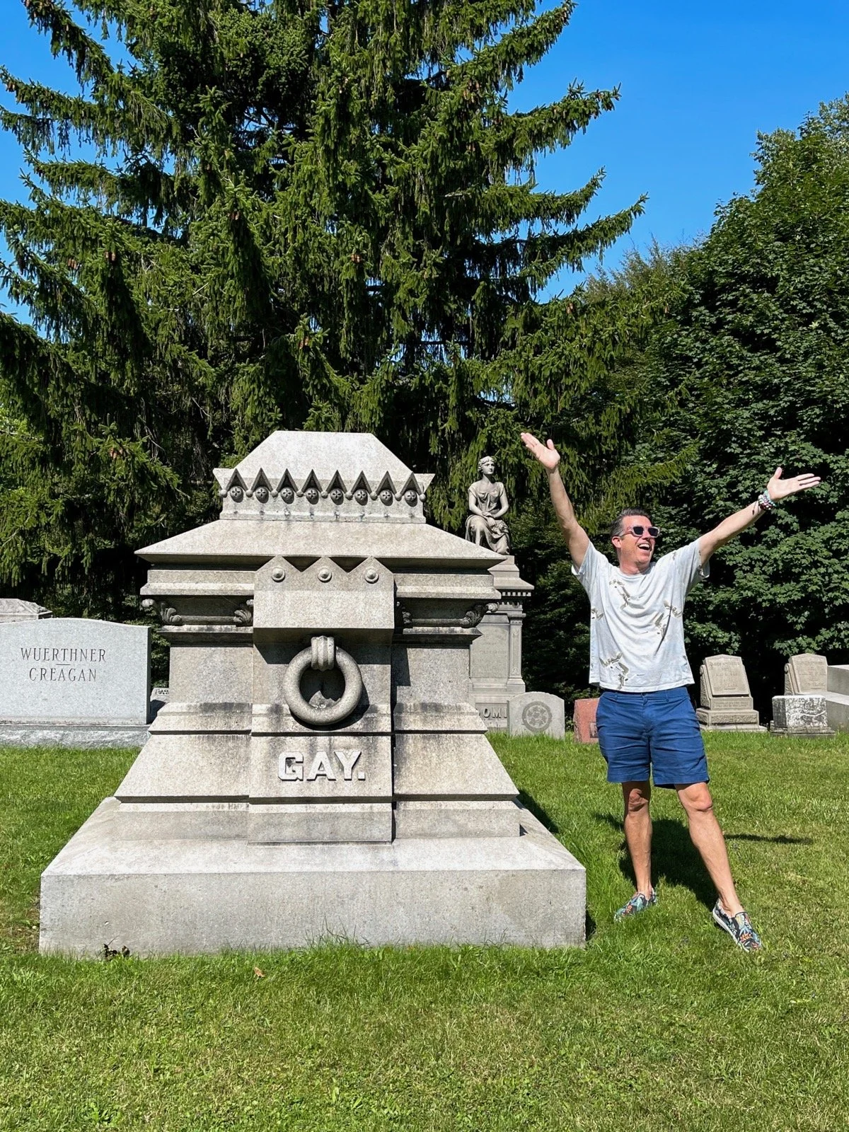 A man poses with arms up by the Gay tomb at Forest Lawn Cemetery