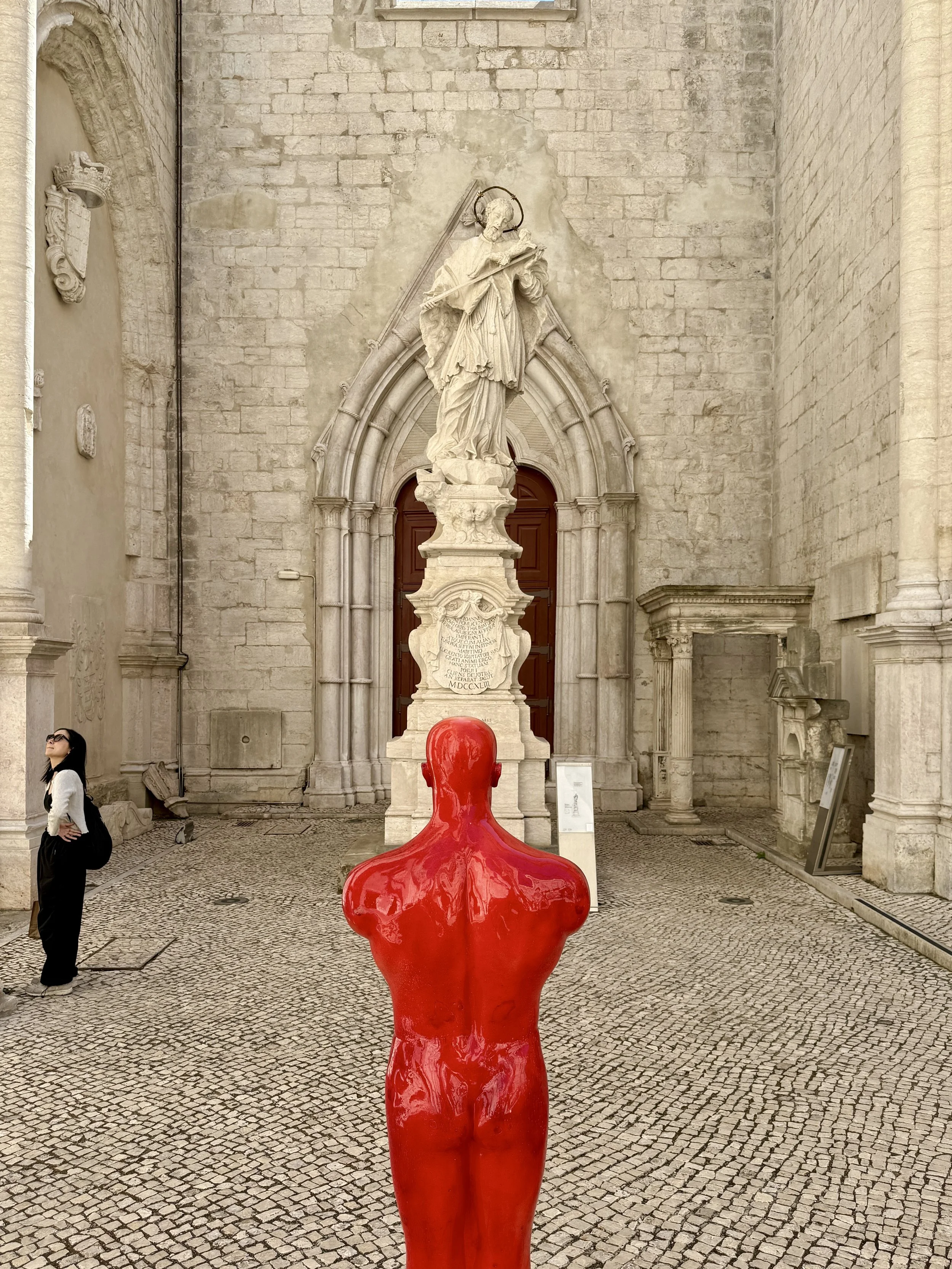 The bright red Homem Vermelho (Red Man), a life-sized sculpture by Sérgio Pombo, in the courtyard of the Carmo museum in Lisbon