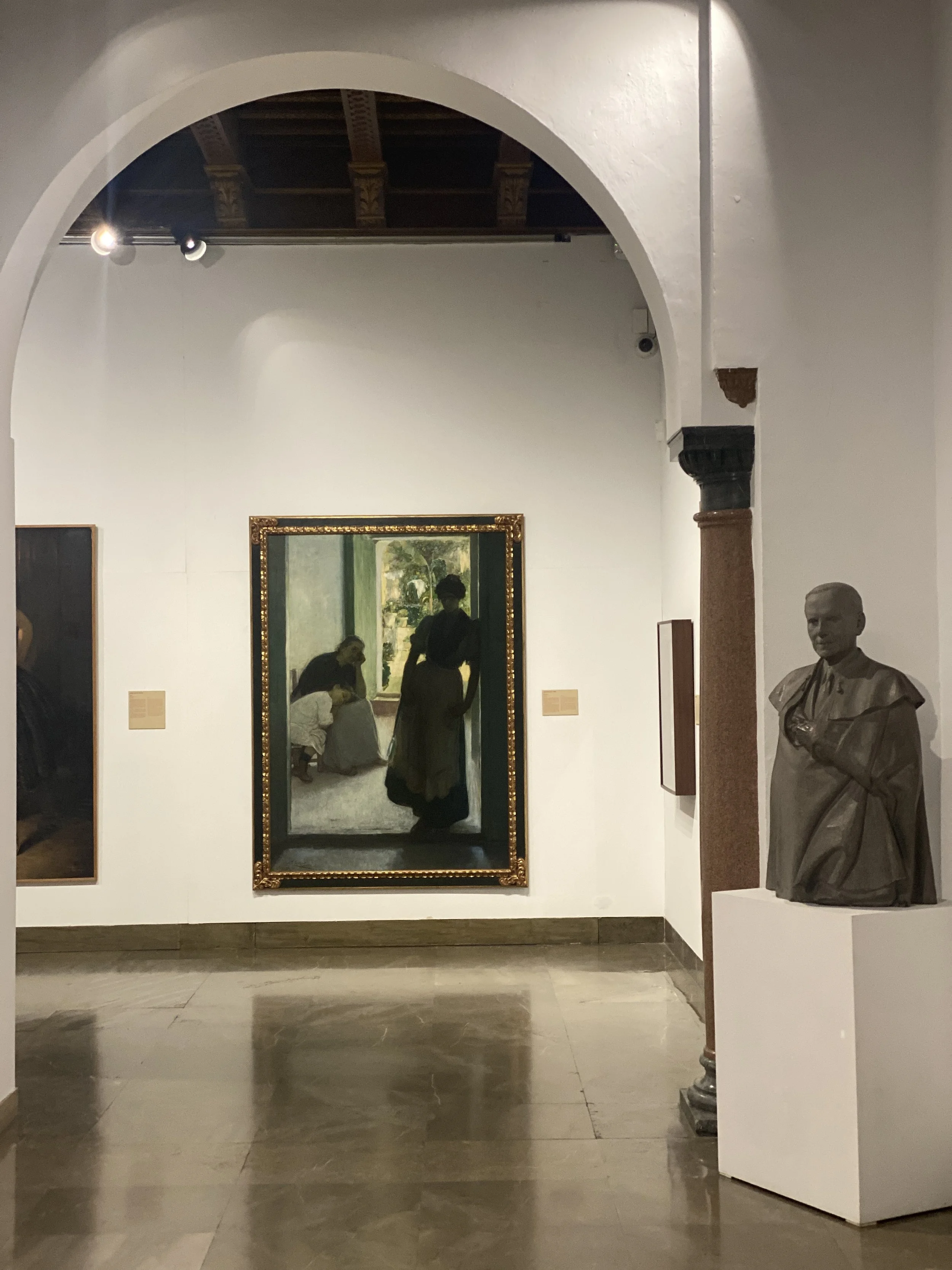 Arched gallery with paintings and bust at the Museo de Bellas Artes de Córdoba