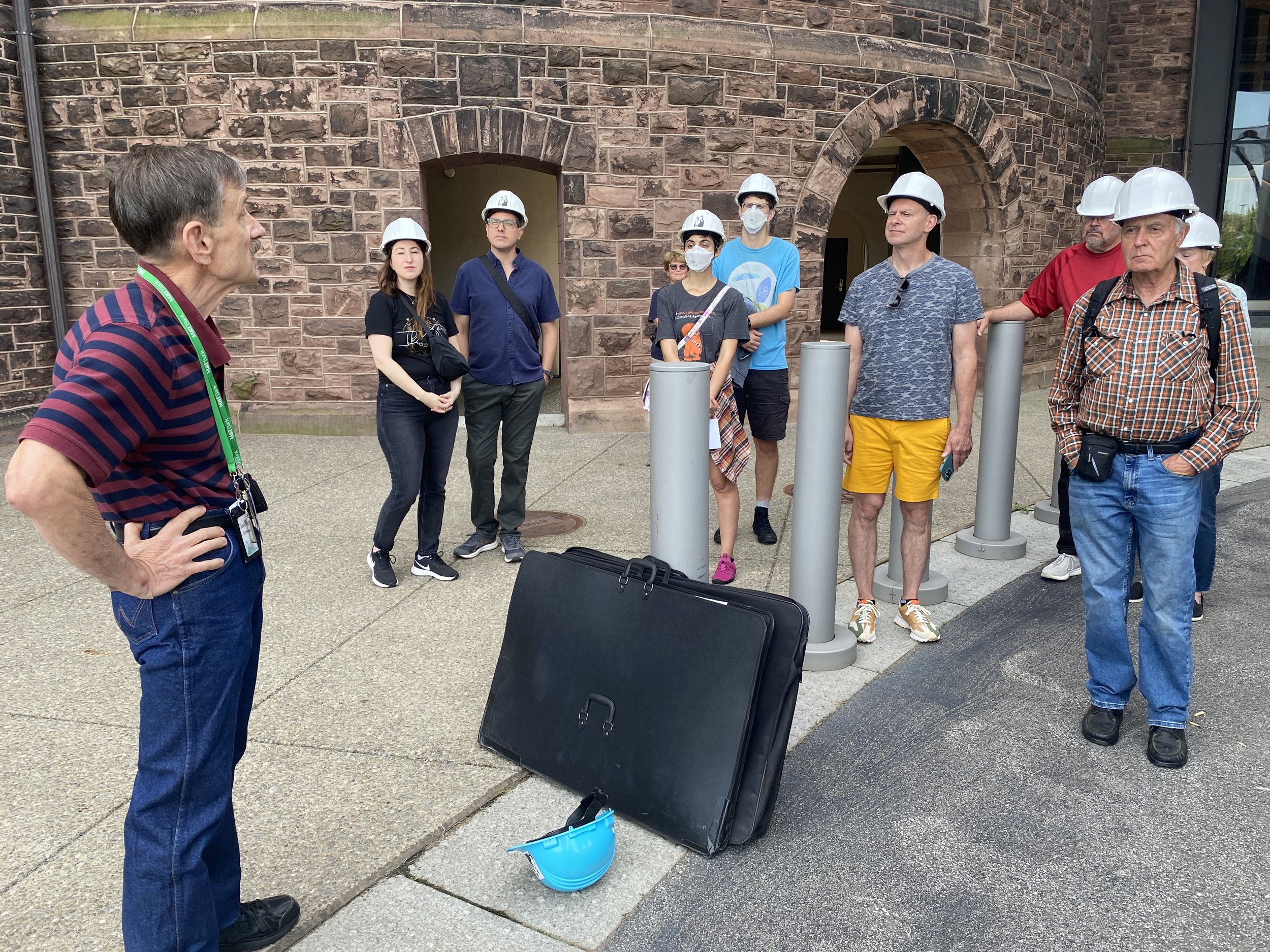 A tour guide talks with a group of people in white hard hats at the Richardson Hotel in Buffalo, New York