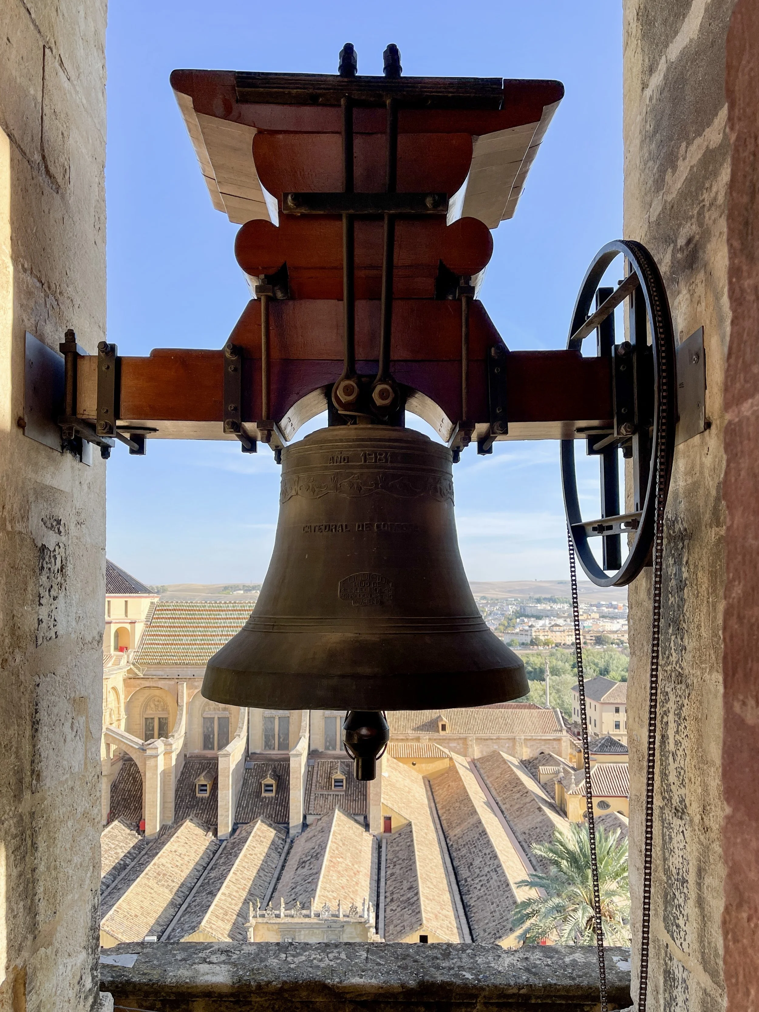 Bell with aerial view of Córdoba, Spain beyond atop the Torre Campanario de la Mezquita-Catedral de Córdoba