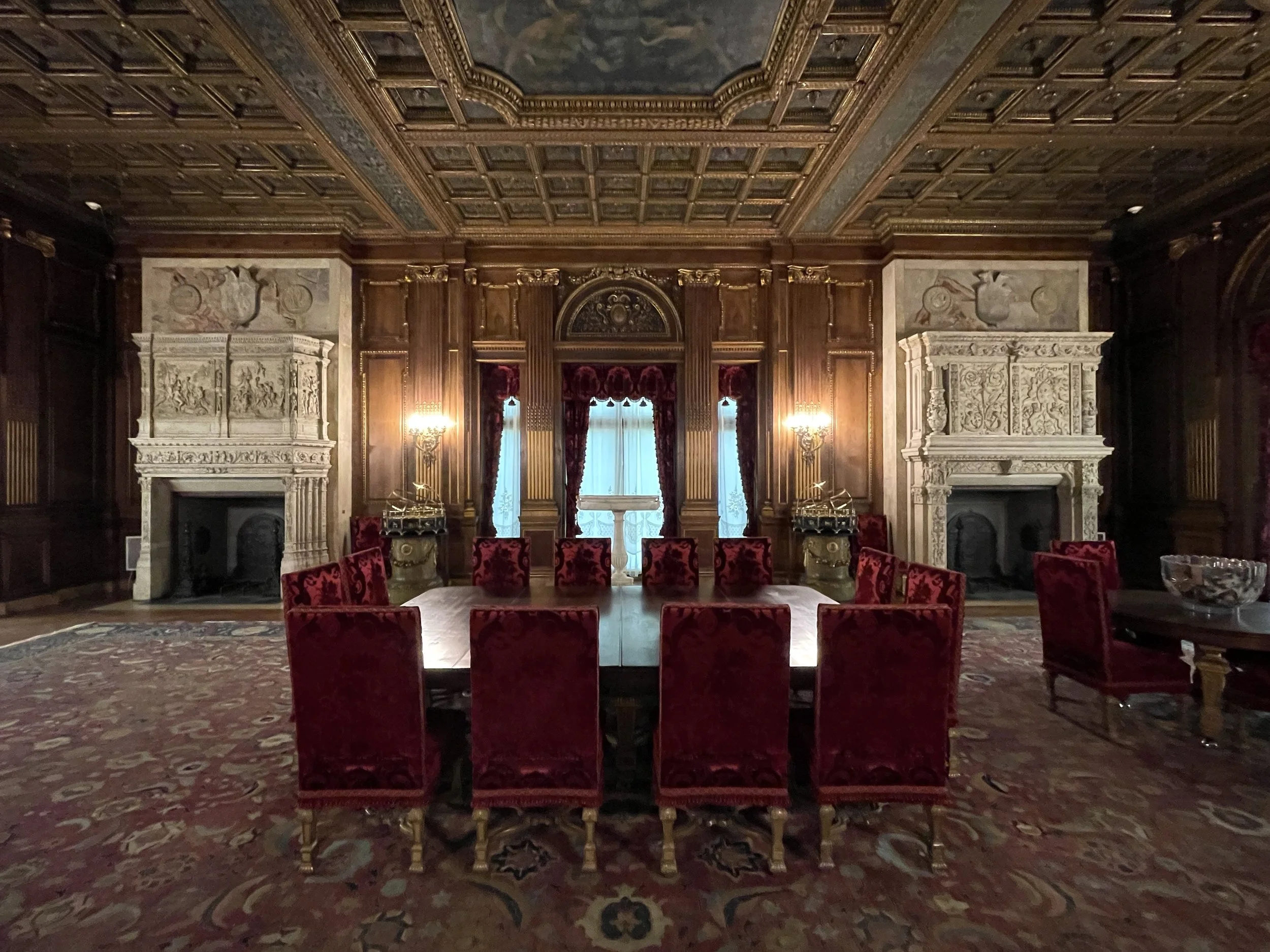 Table with red velvet chairs and two fireplaces in the dining room at the Vanderbilt Mansion