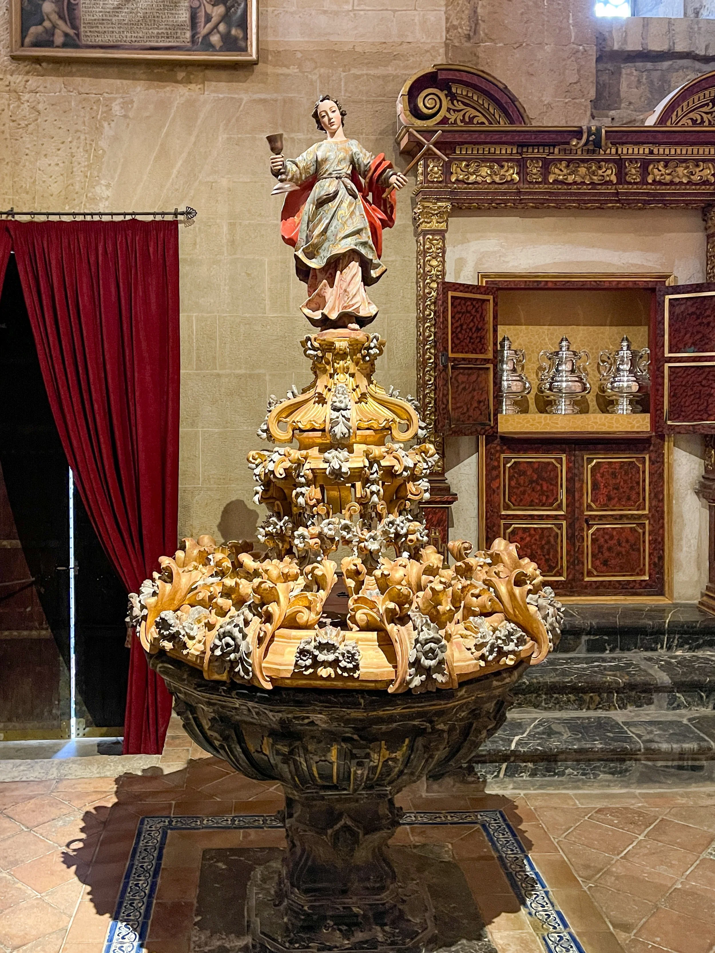 Religious statue atop strange orange fountain and crownlike structure