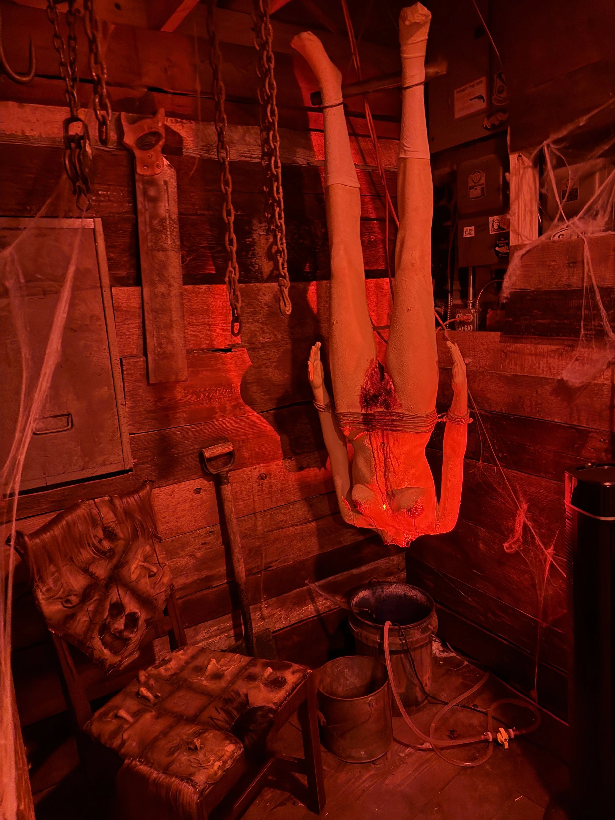 Red light showing a headless female mannequin hanging upside down to show Ed Gein's final victim in the Graveface Museum in Savannah