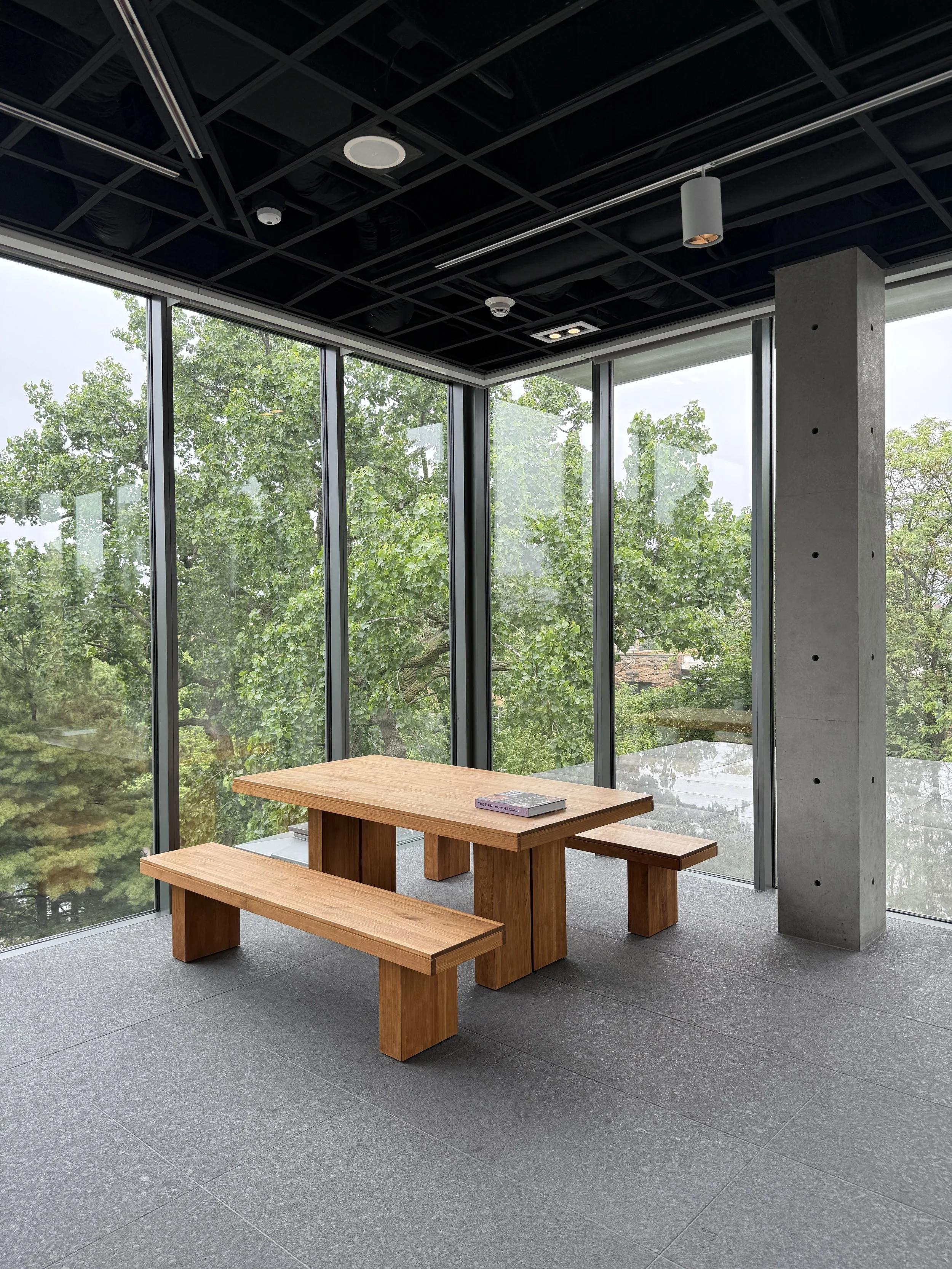 A table and benches by big windows in a quiet nook at Wrightwood 659 in Chicago