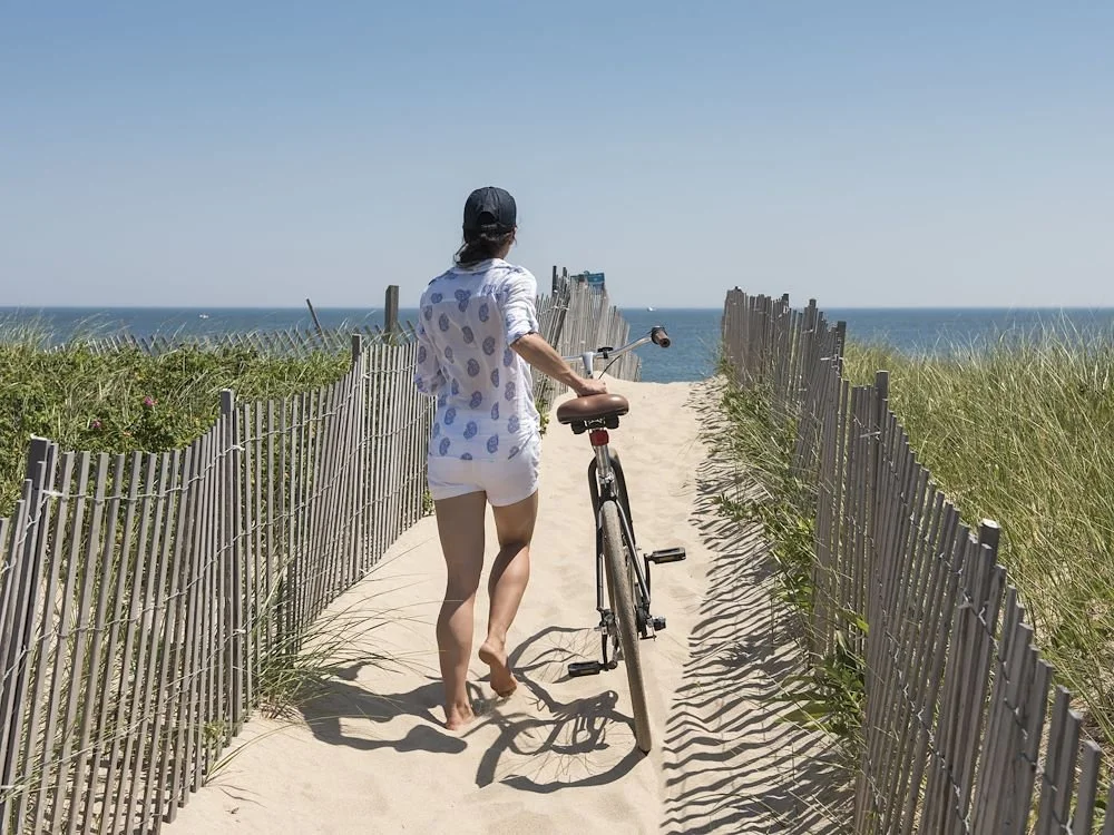 Woman walking her beach between fences to Nantucket beach