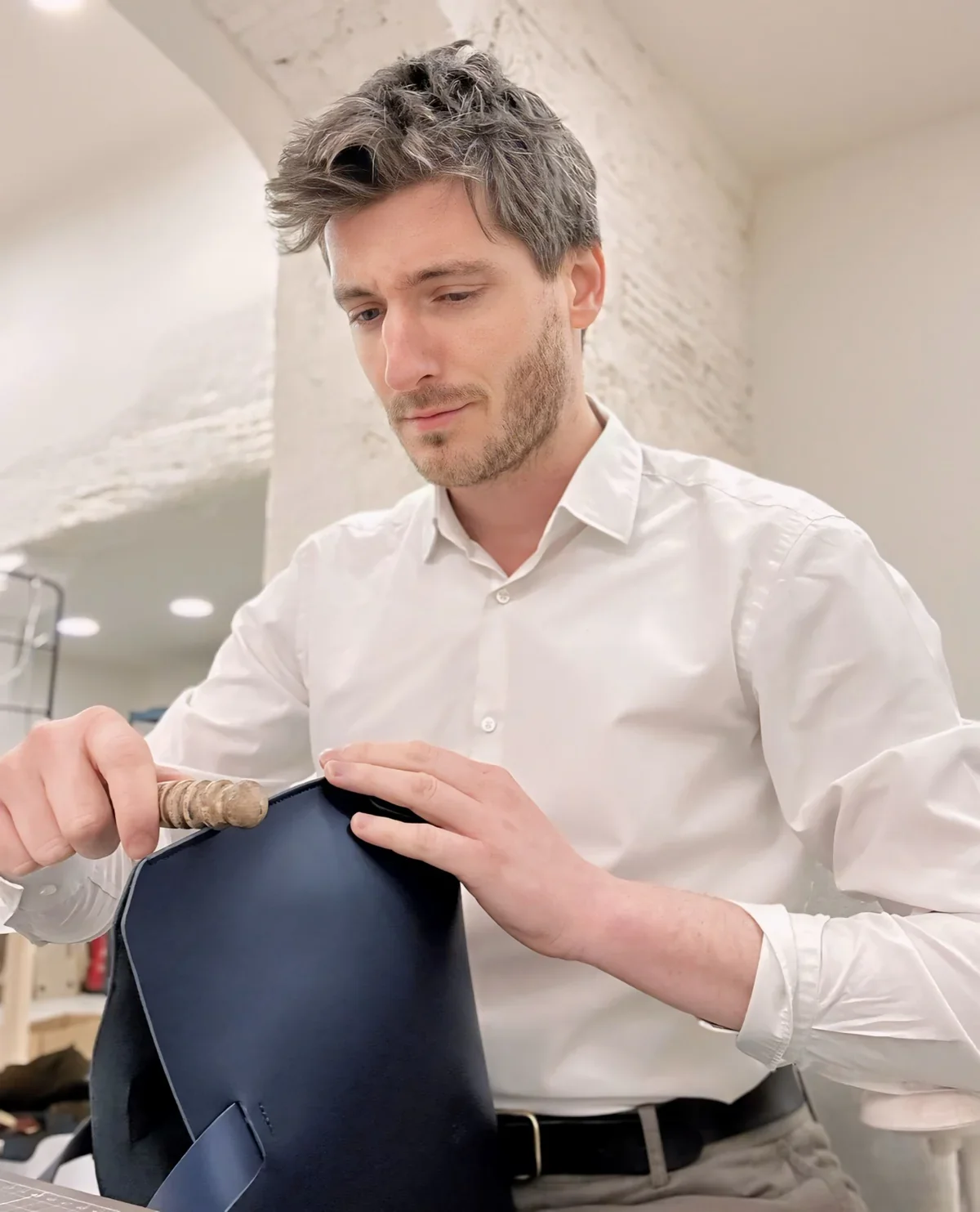 Manuel Dreesmann, founder of Atelier Madre, handcrafts a laptop sleeve in navy blue leather
