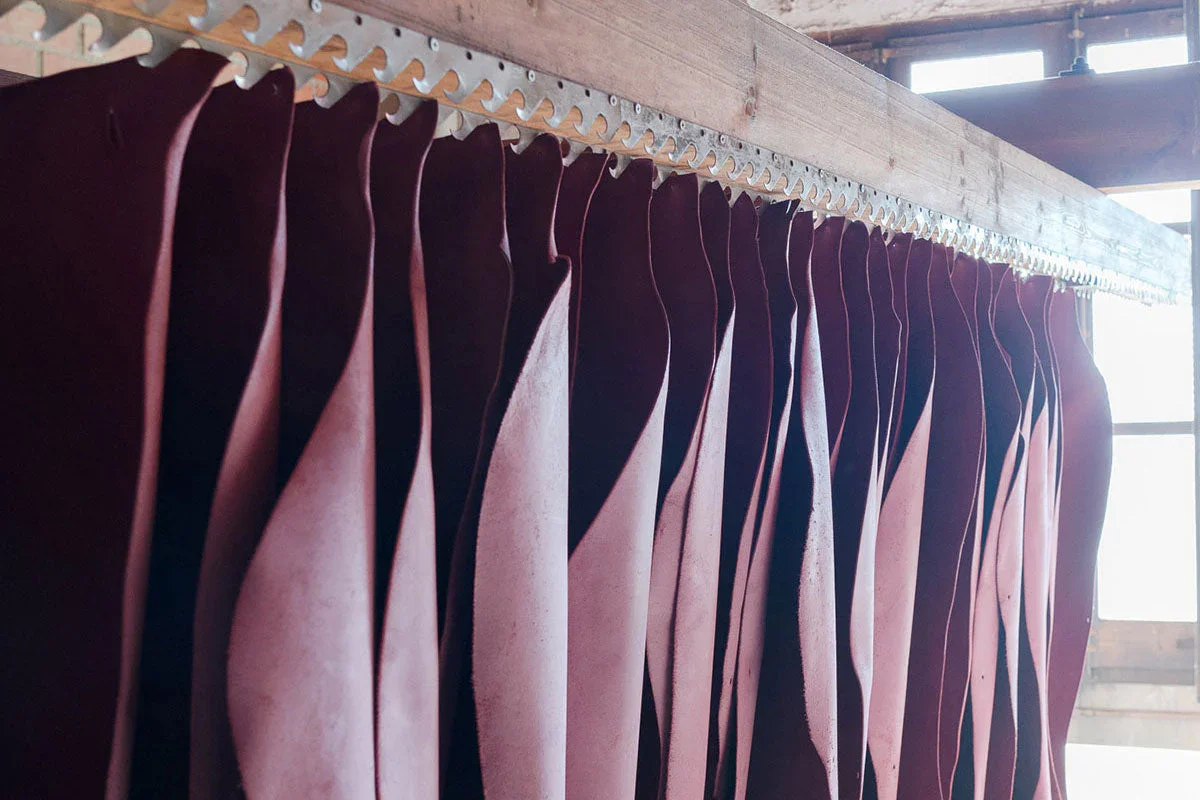 Pieces of leather hang at a tannery