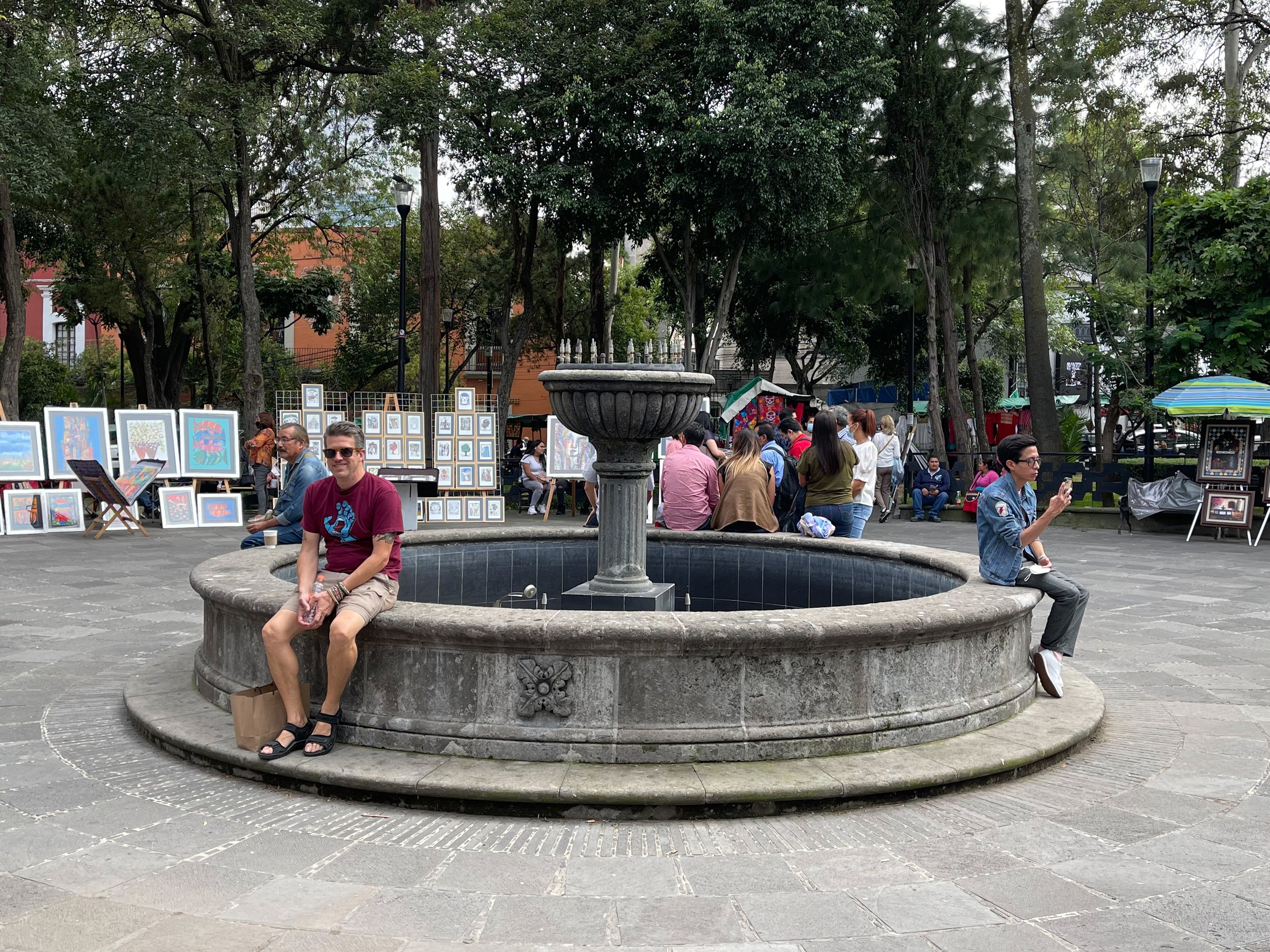 Men sitting on fountain in plaza of el Bazar Sábado