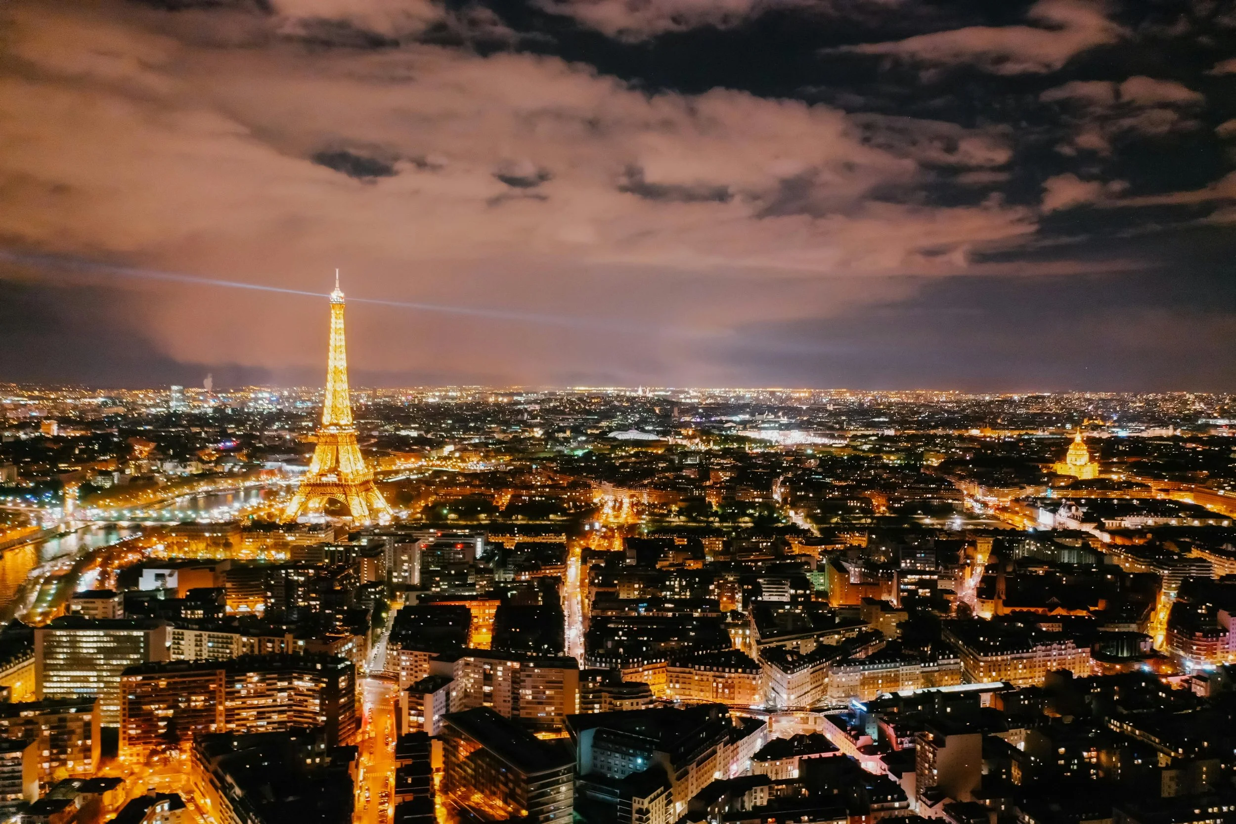 Aerial view of Paris at night, with the city and the Eiffel Tower lit up