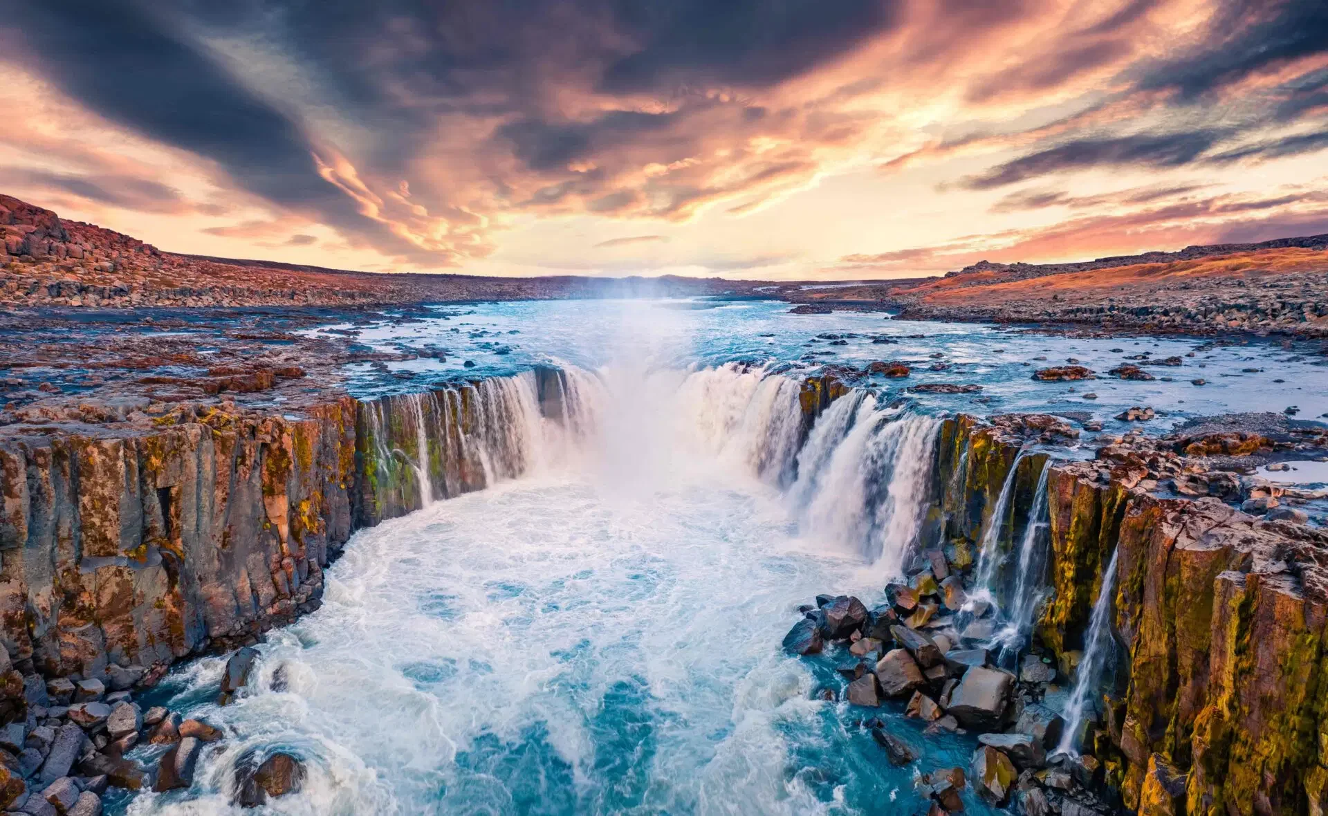 A curved rock formation with waterfalls at Selfoss, Iceland