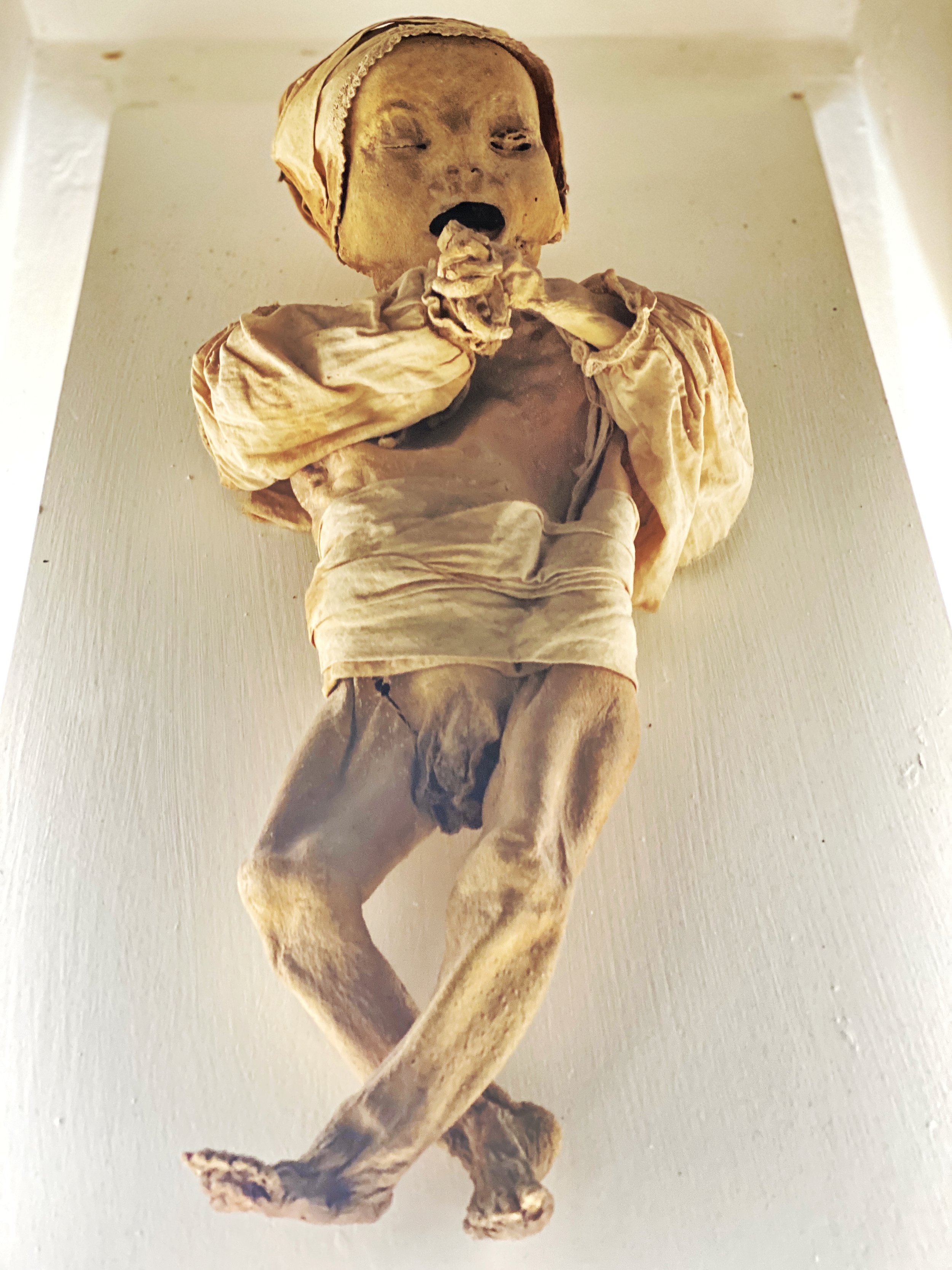 Mummy of baby in dress at the Mummy Museum of Guanajuato