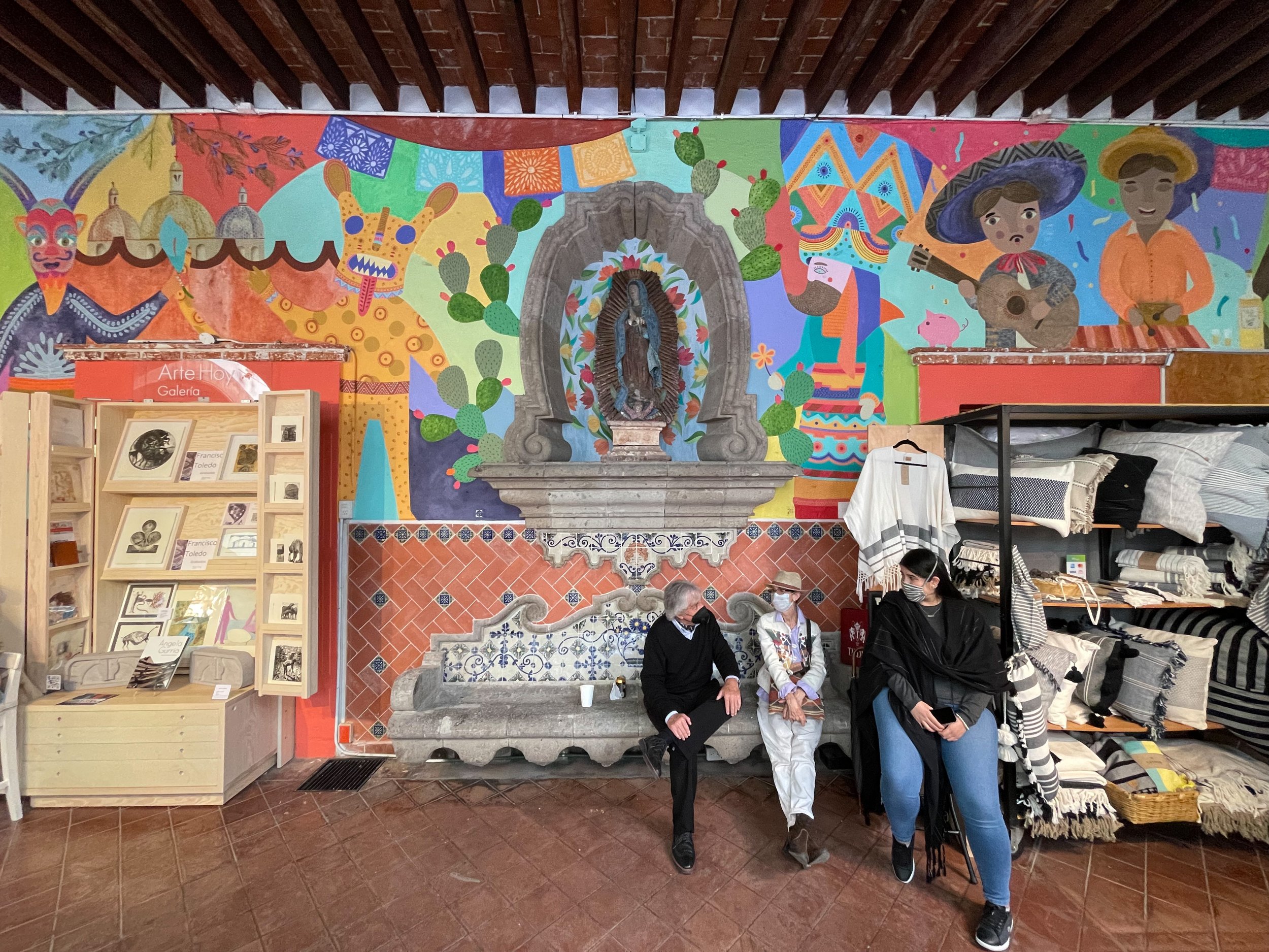 People sitting below mural at el Bazar Sábado