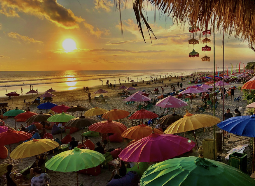 Brightly colored umbrellas on the beach at sunset in Seminyak on Bali