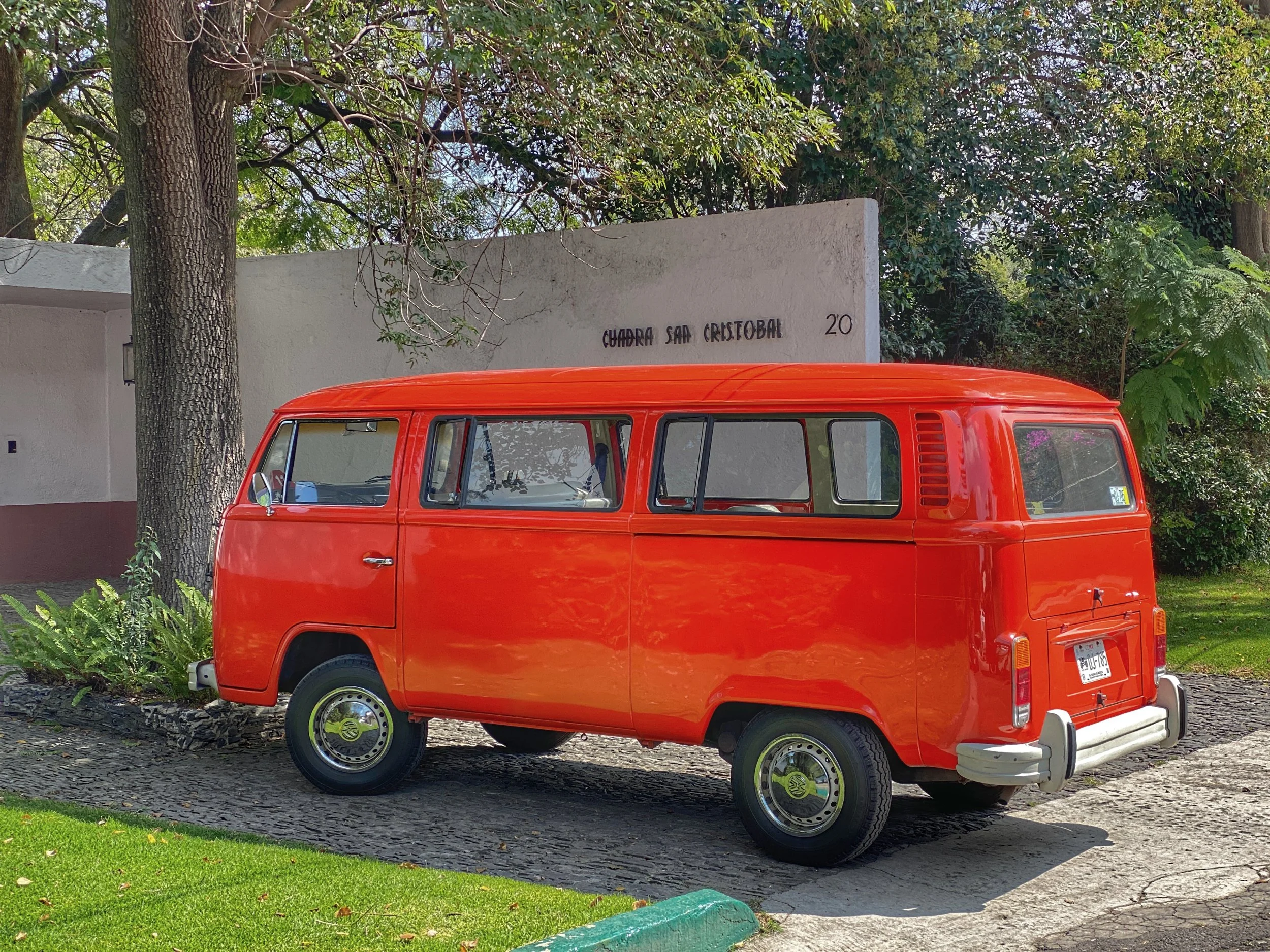 An orange-red classic VW bus in front of Cuadra San Cristobal