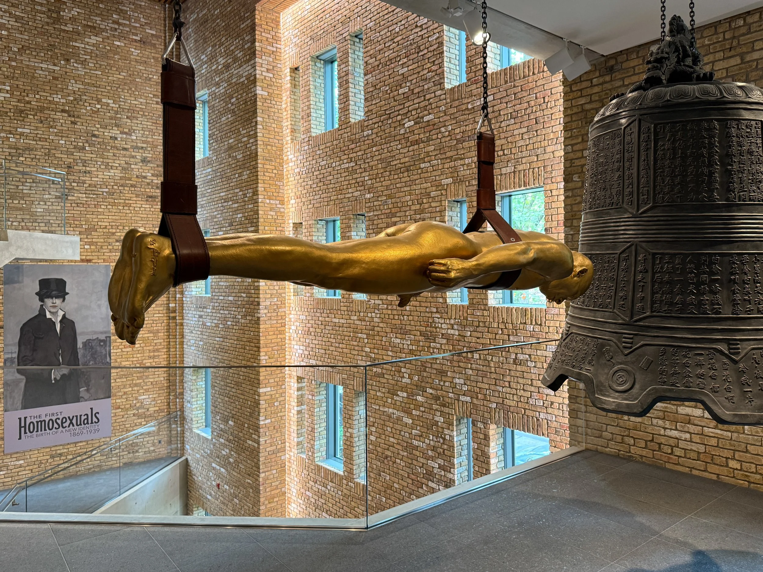 Peace 1 by Zhang Huan, a sculpture of a nude golden man about to ring a large metal bell, at Wrightwood 659 in Chicago, during The First Homosexuals exhibit