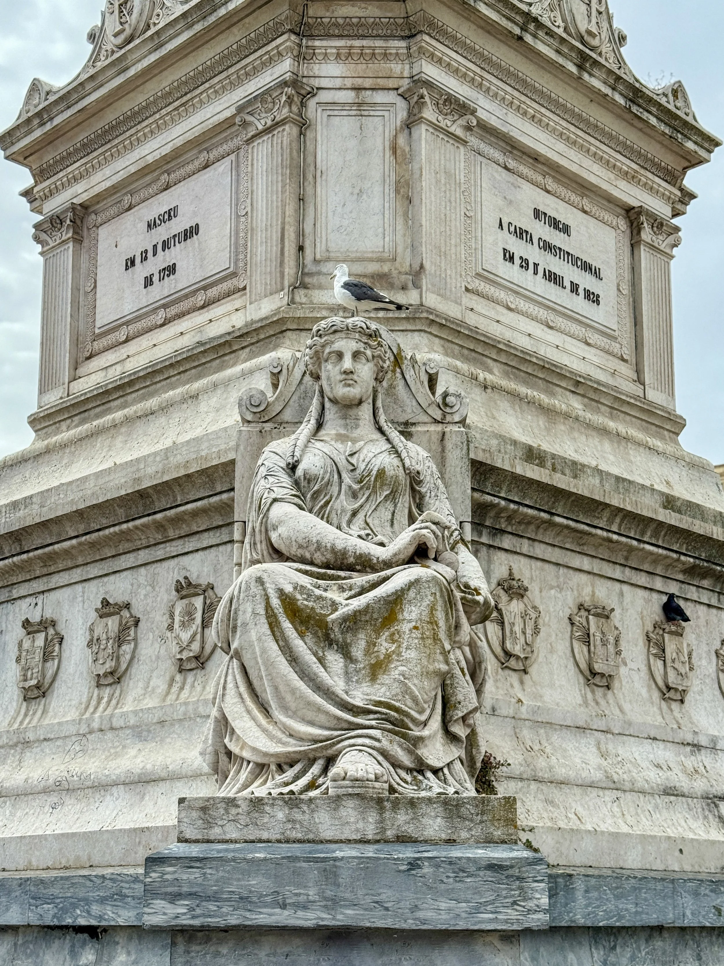 A statue of a woman representing Justice or Wisdom, with a seagull perched upon her head, in Rossio Square in Lisbon, Portugal