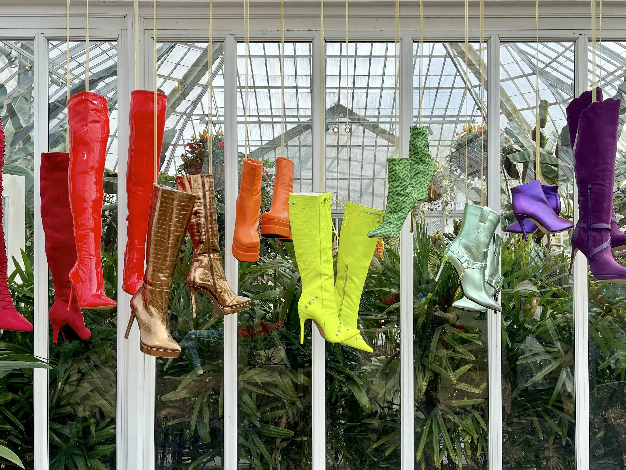 Rainbow array of high boots hanging in the Phipps Conservatory in Pittsburgh