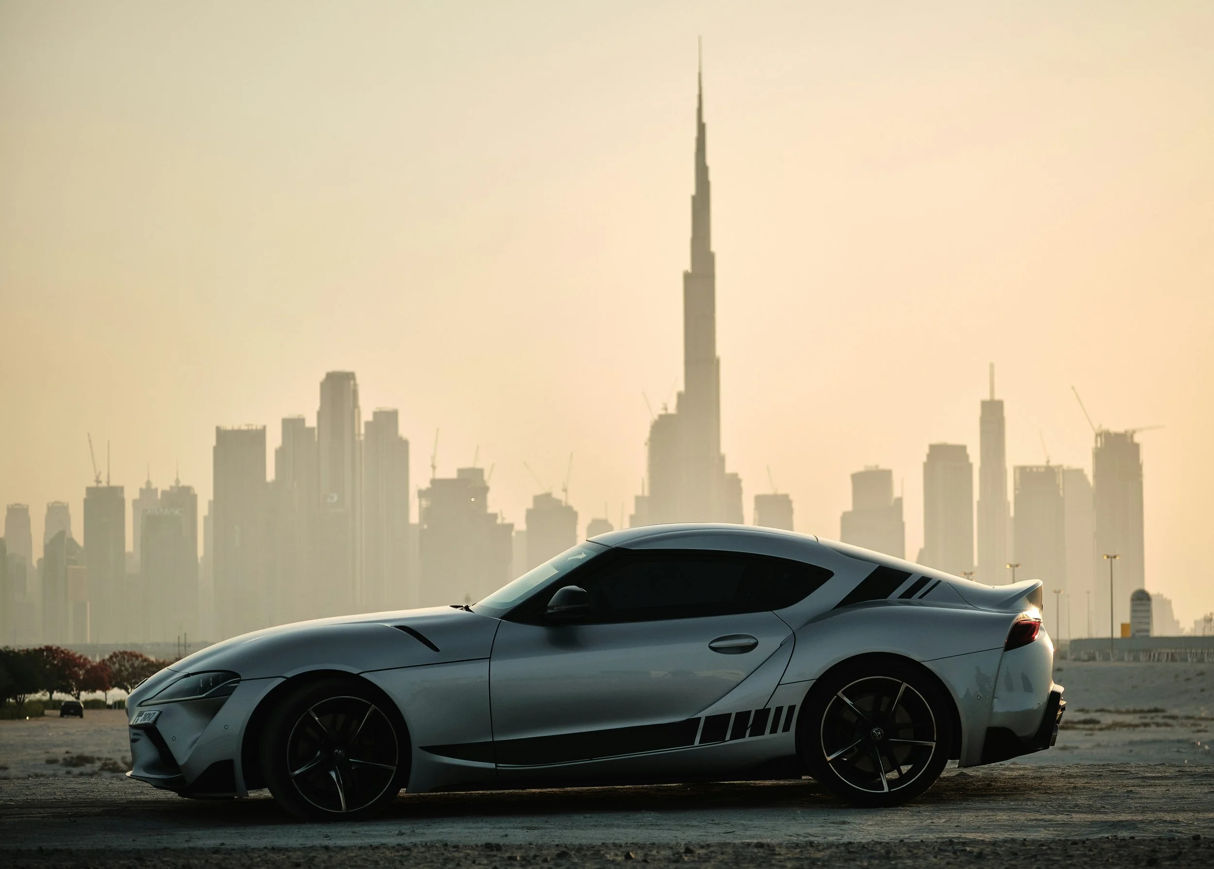 A sports car parked in front of a hazy view of the Dubai skyline