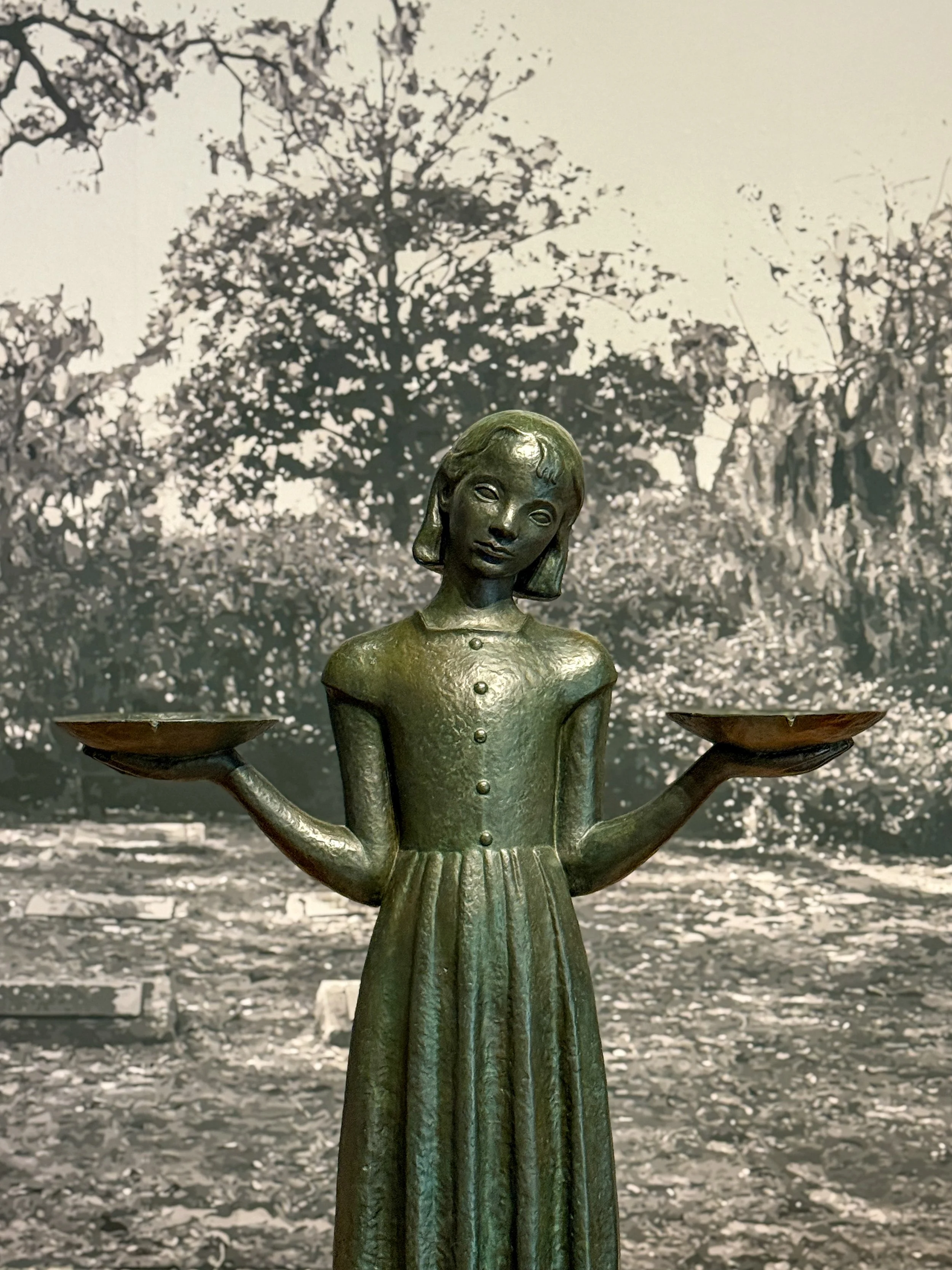 The statue of the Bird Girl statue, holding two bowls in her hands, in an exhibit at the Telfair Academy in Savannah, Georgia