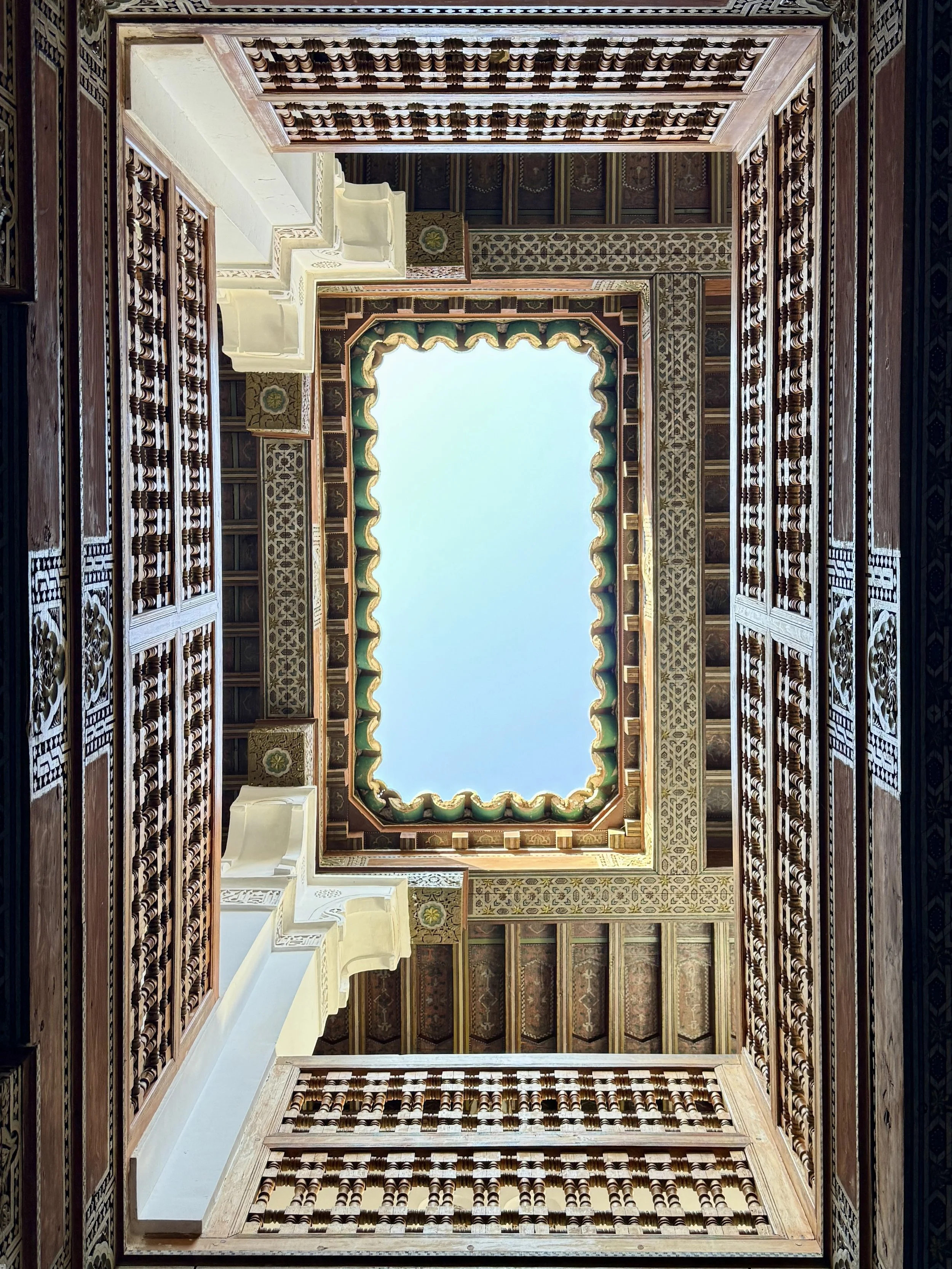 Looking up at an opening in the roof with elaborately carved cedarwood at Ben Youssef Madrasa