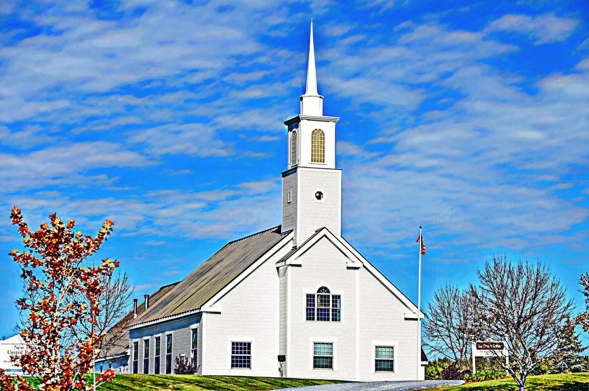 A white church with steeple under a blue sky
