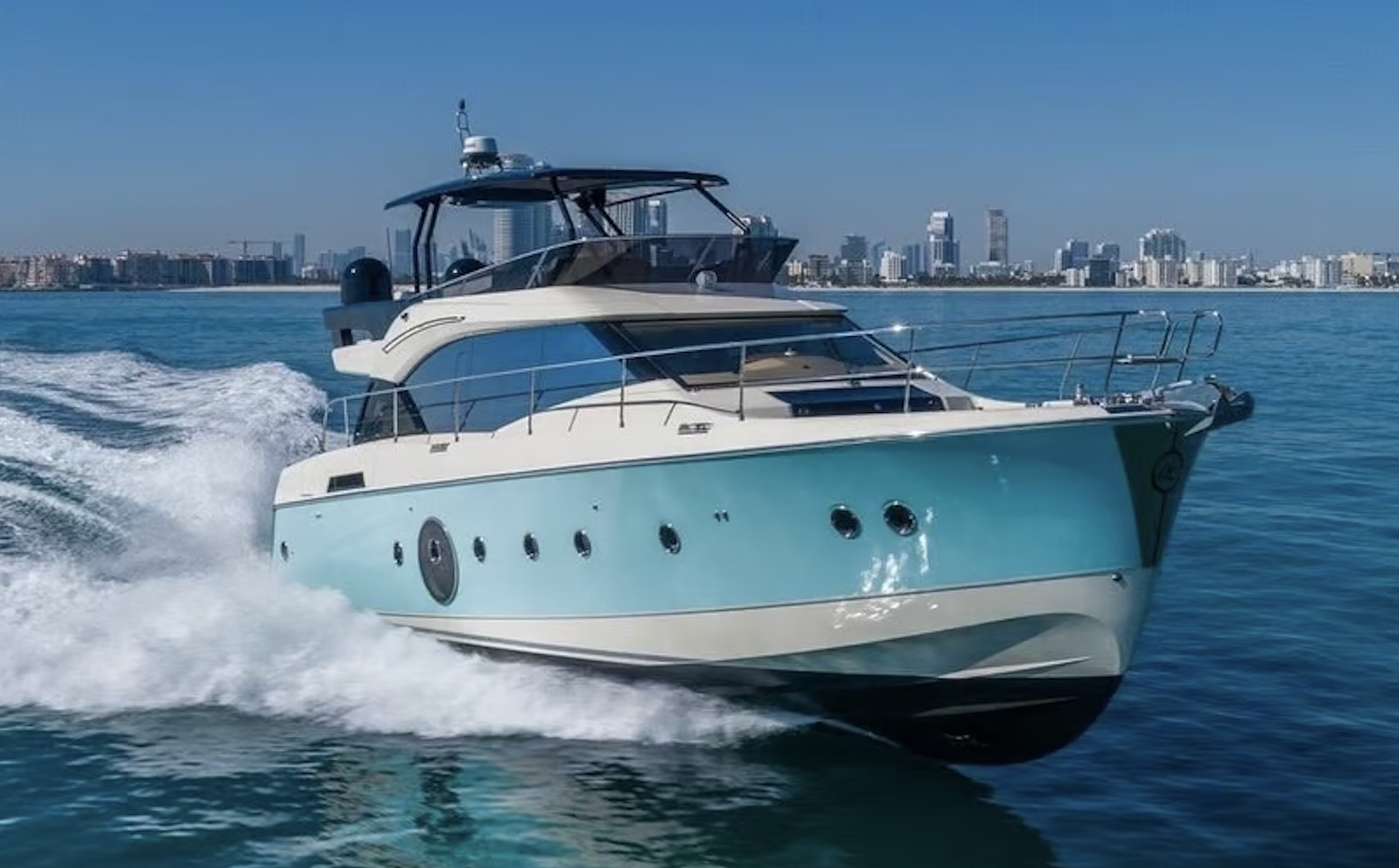 A light blue and white yacht cruises through the water off the coast of Dubai
