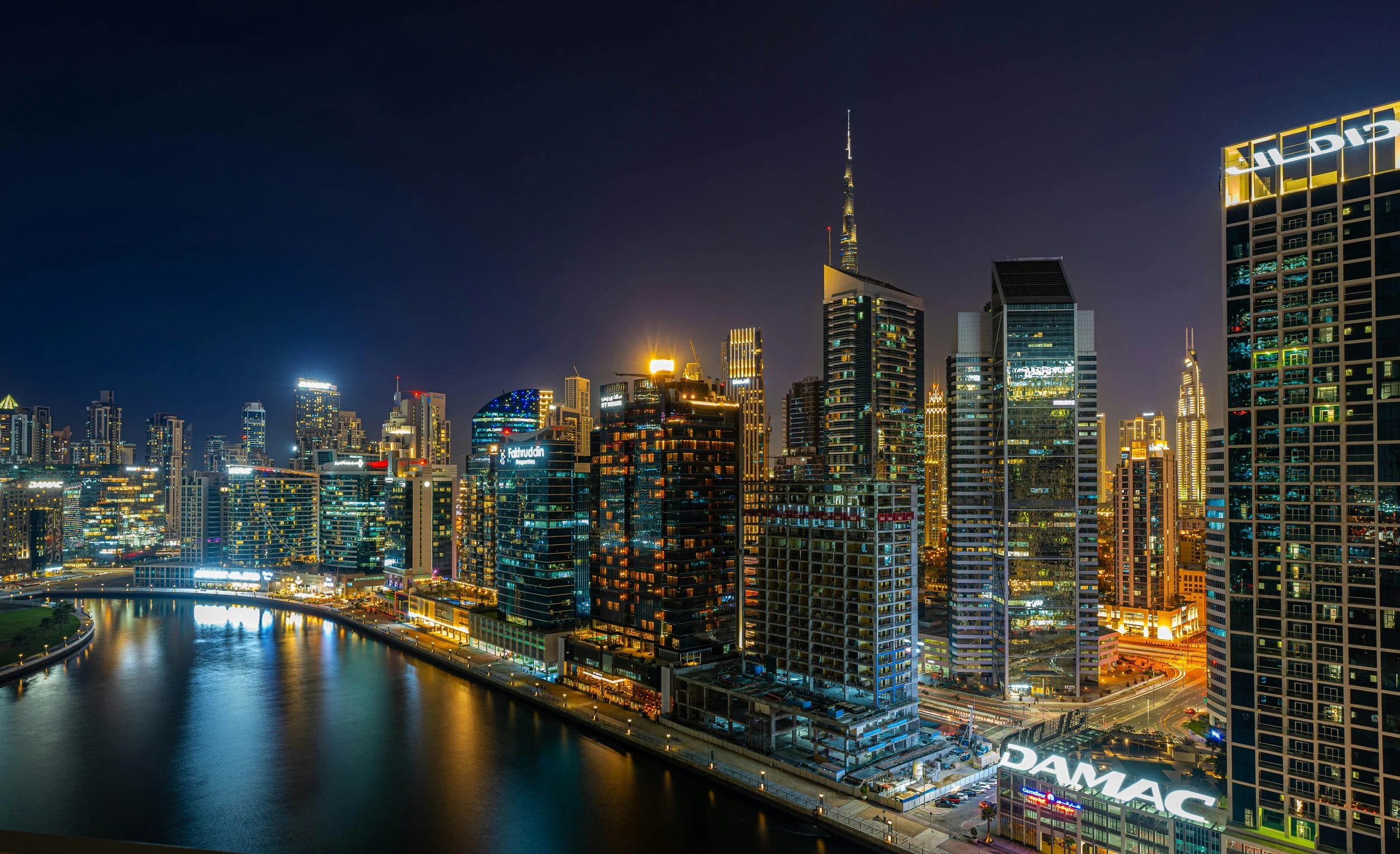 The Dubai skyline at night along a waterway