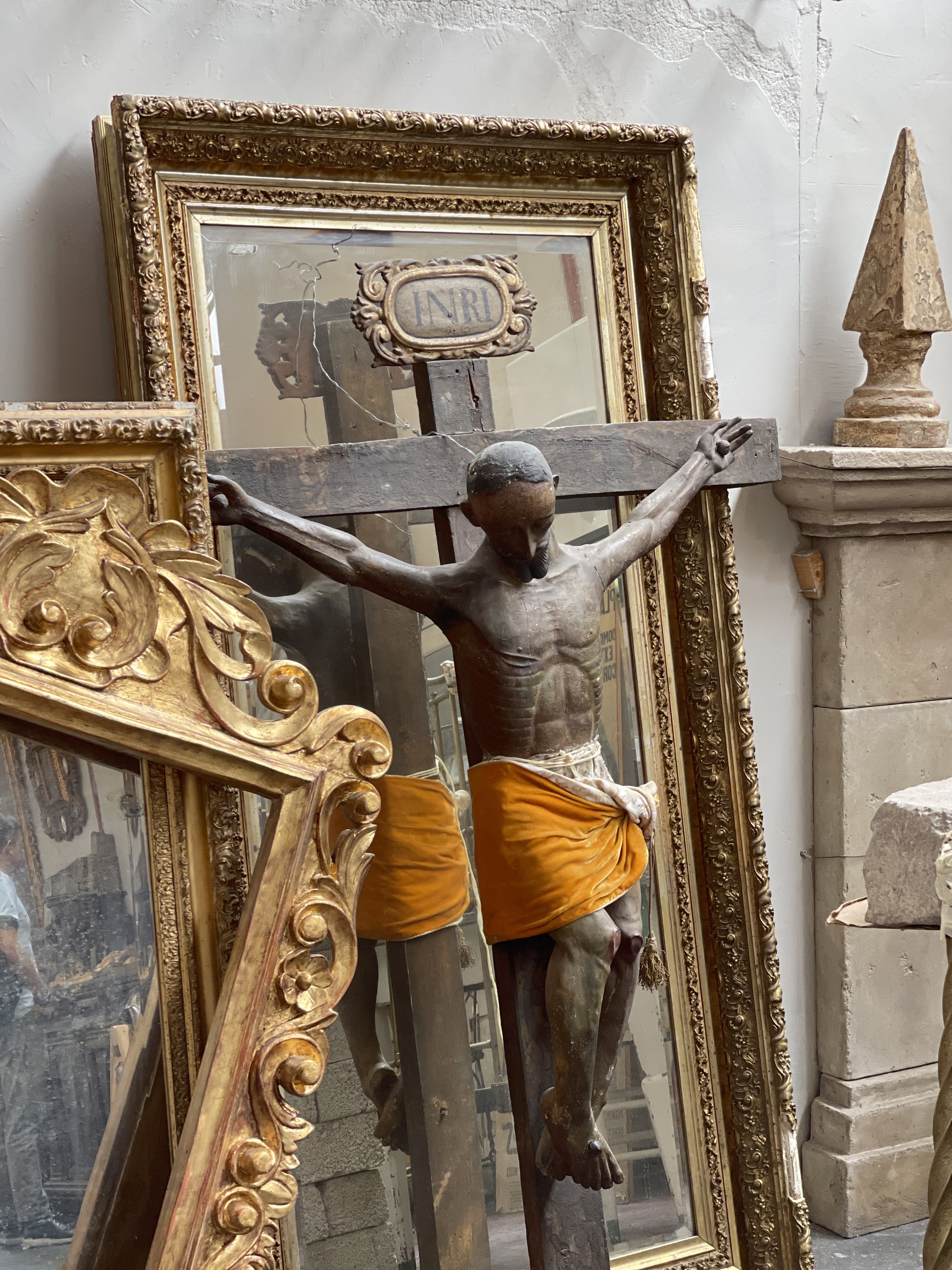 Antique store with Jesus on the cross in orange loincloth leaning on stacks of framed art