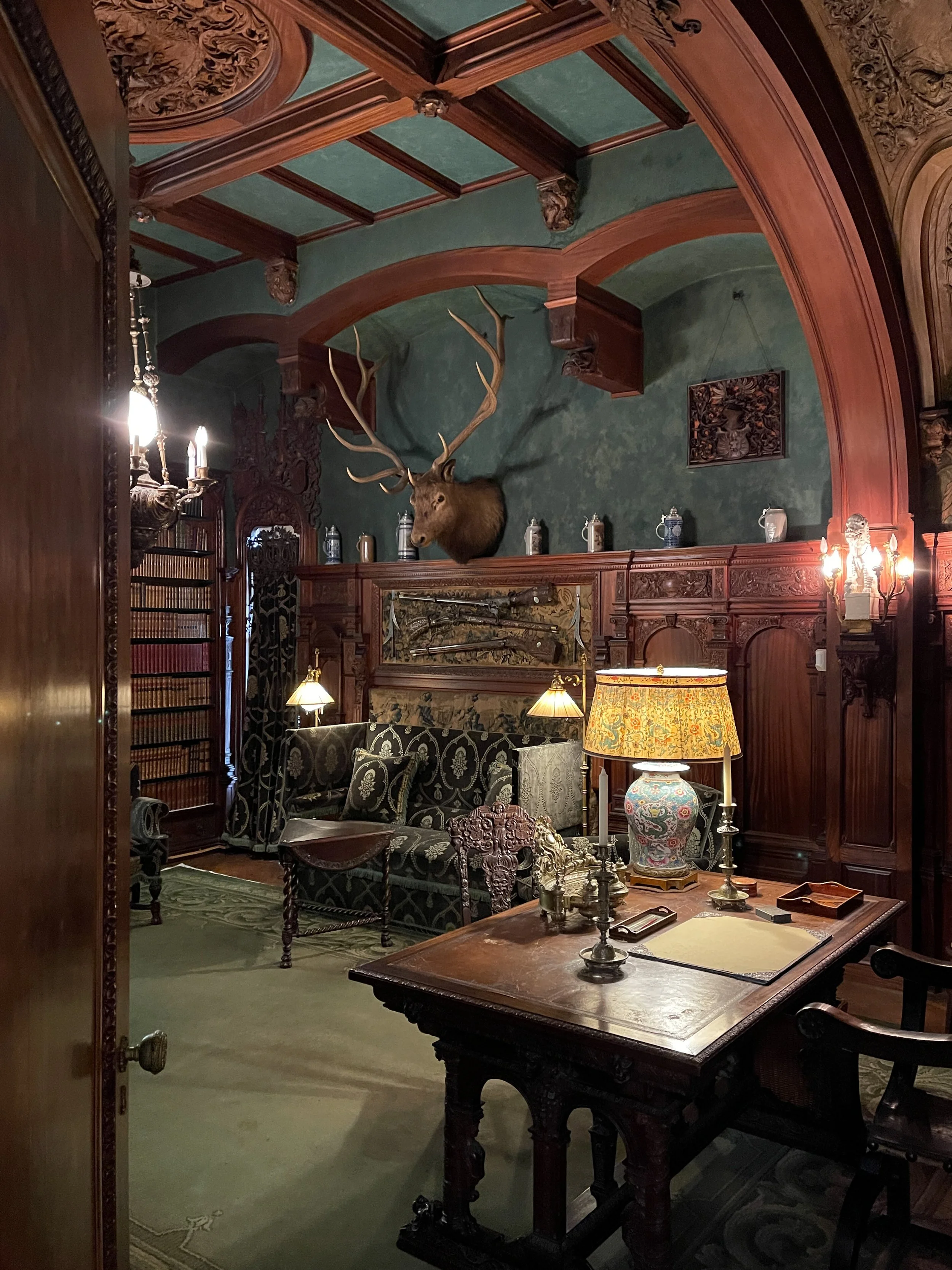 Frederick's den at the Vanderbilt Mansion, with deer head, desk with lamp and setee