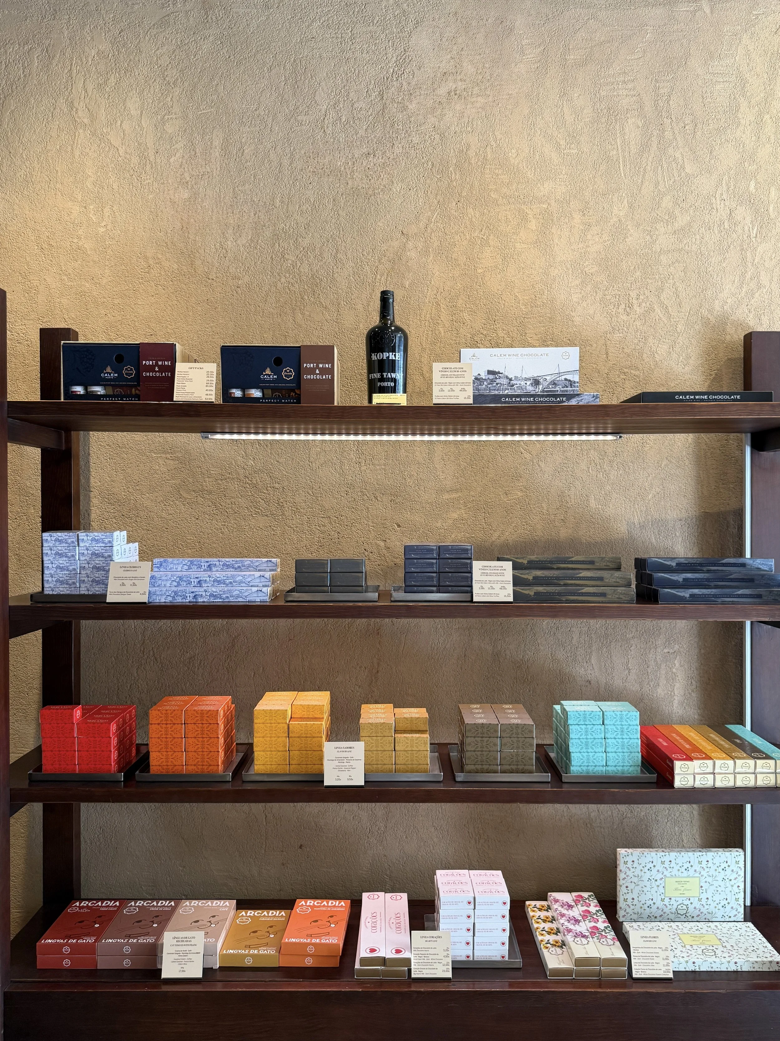 Wooden shelves hold an array of packaged chocolates filled with Cálem port wine, artisanal truffles and Línguas de Gato (cat tongues) at Arcadia chocolate shop in Lisbon, Portugal
