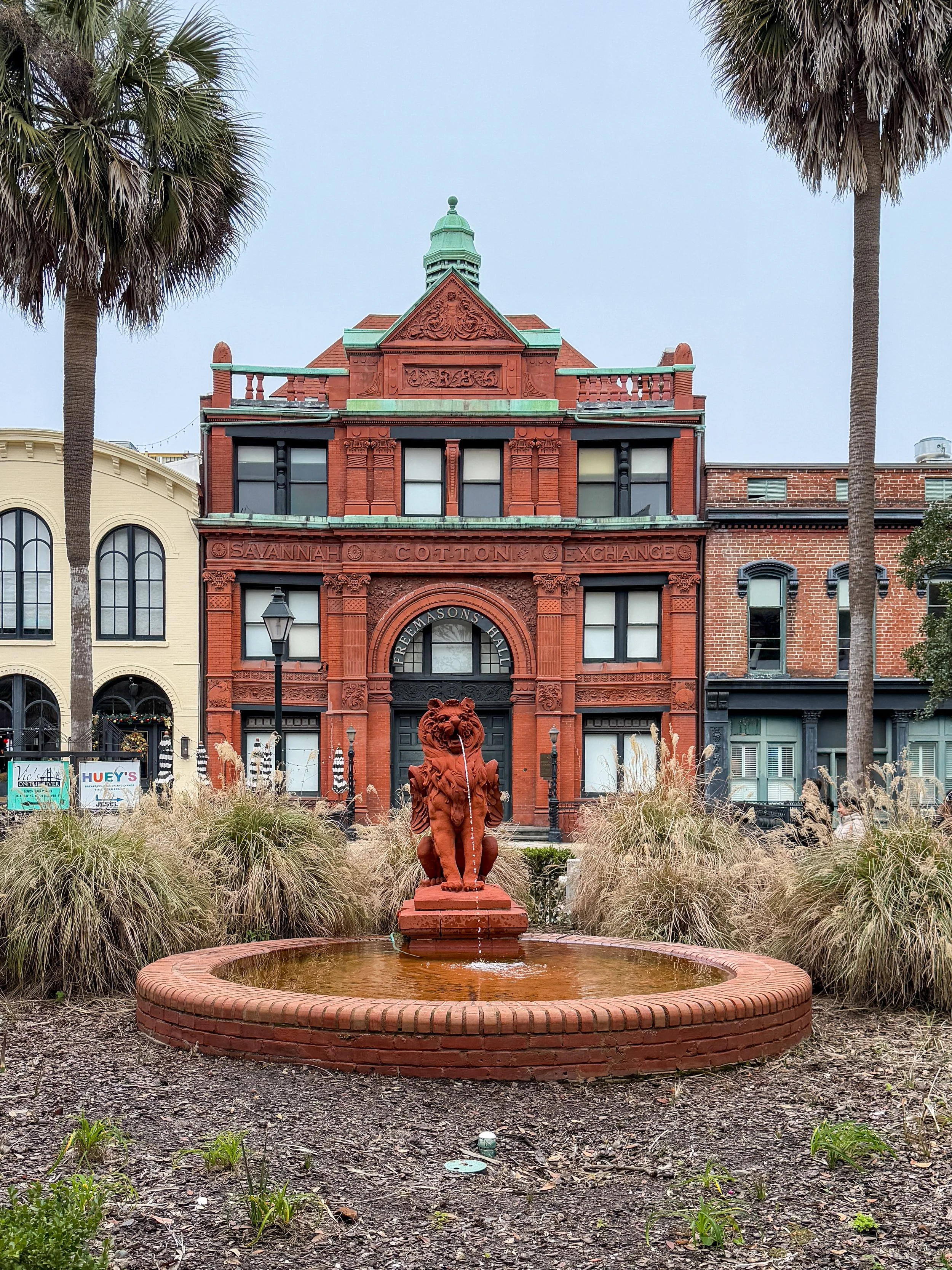 Brick exterior of Freemasons Hall in Savannah, Georgia, with a fountain of a lion spouting water out front