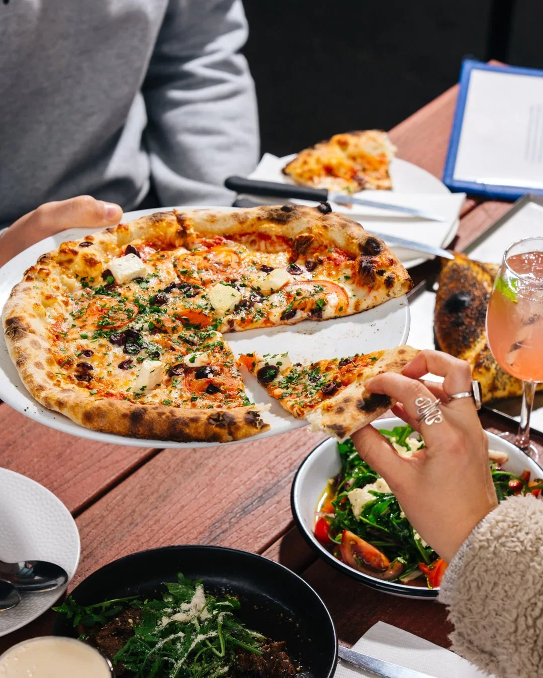 A person takes a piece of pizza while dining at the Lady of St Kilda in Melbourne, Australia
